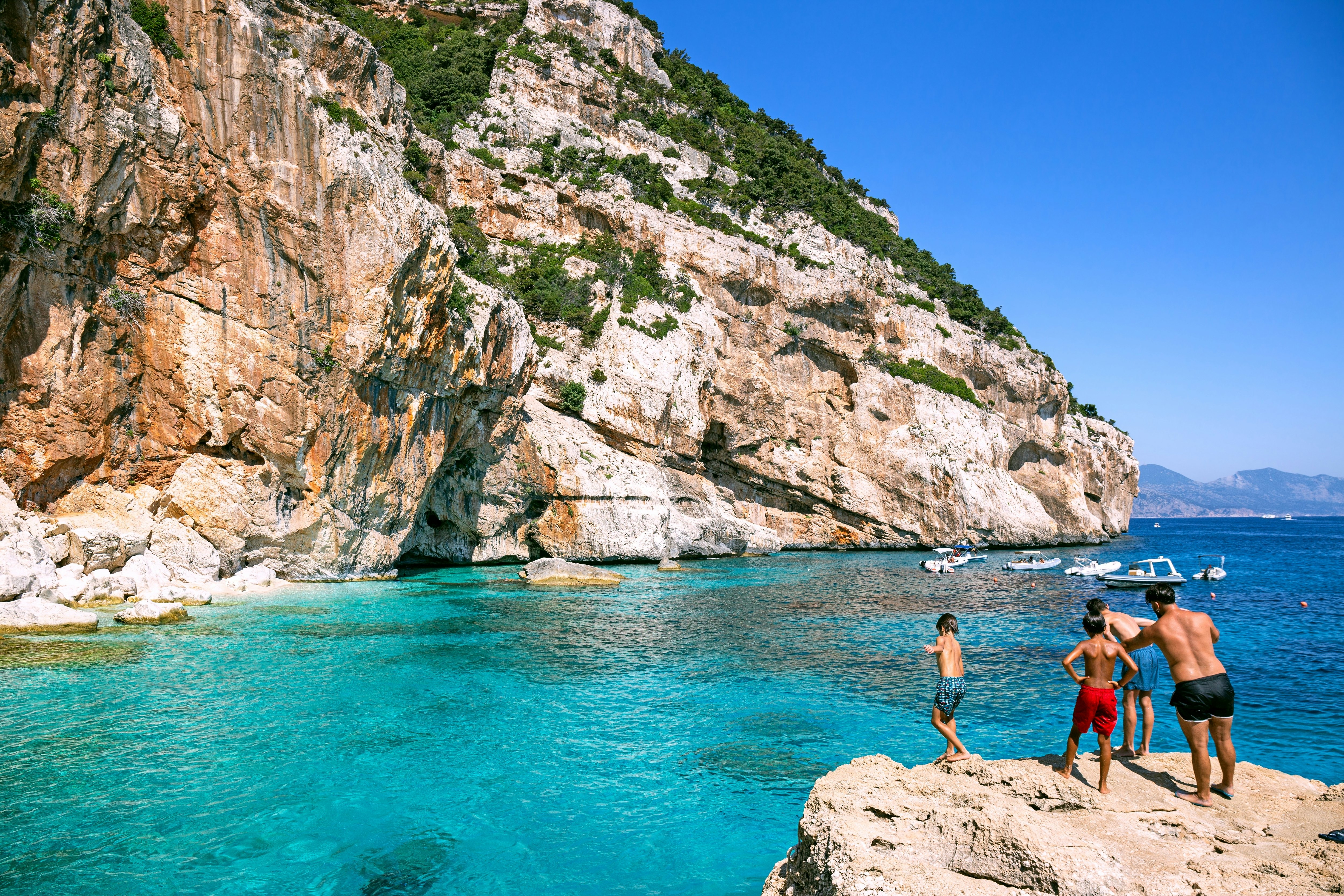 People jumping from the cliff into turquoise waters of Cala Mariolu, Sardinia