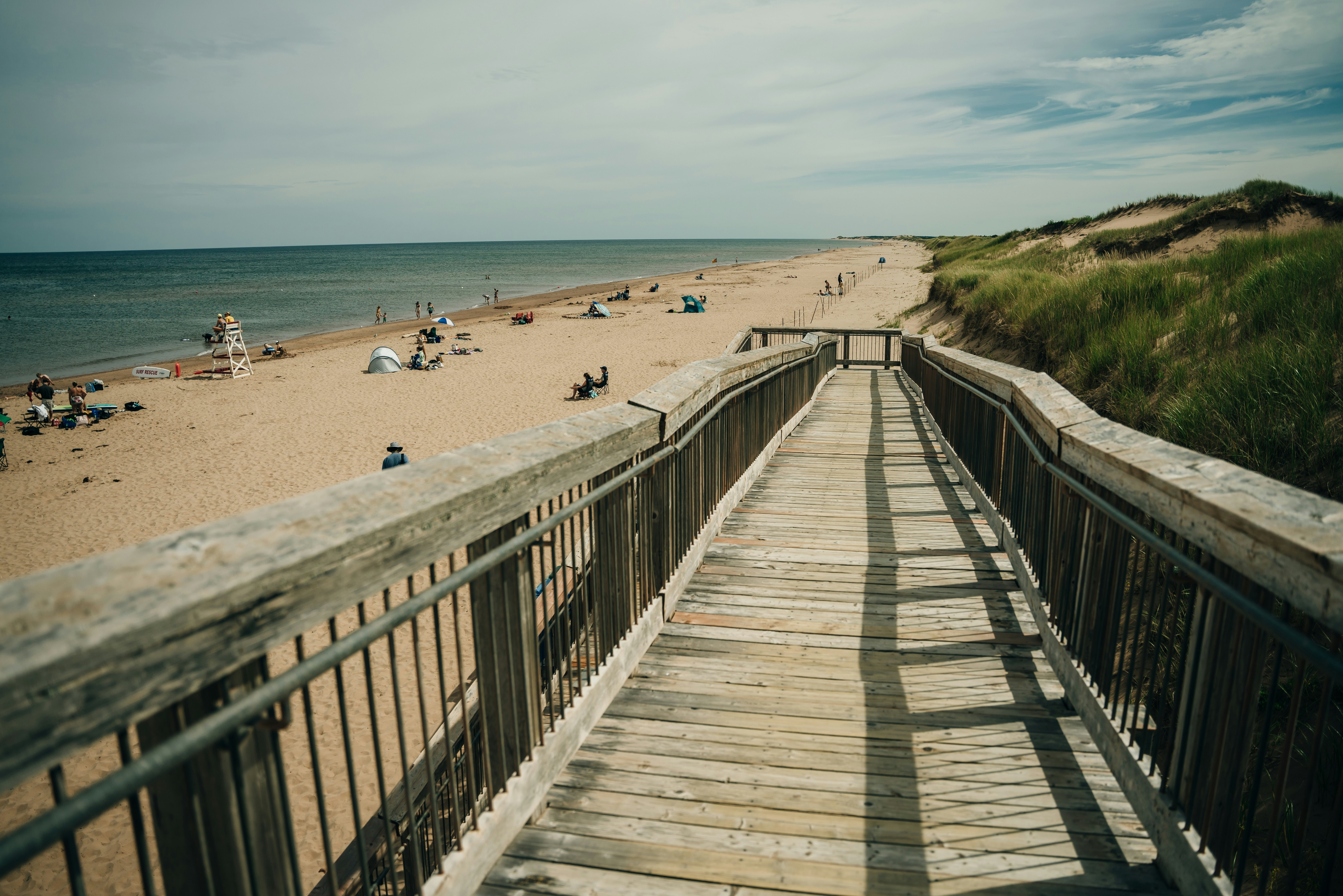 A wooden ramp leads past dunes down to a sandy oceanfront beach.