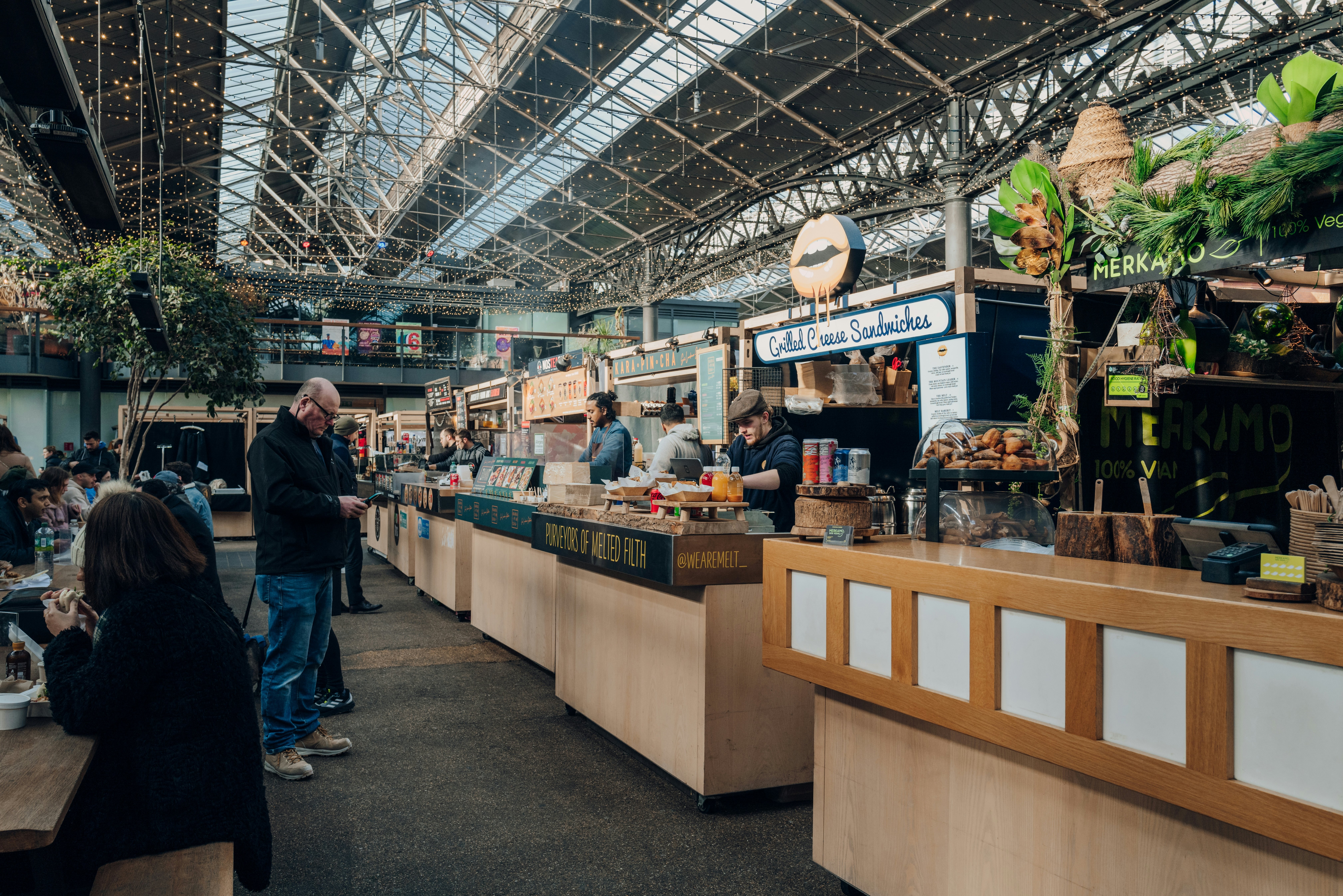 Row of food market stalls inside Old Spitalfields Market, one of the finest Victorian Markets in London with stalls offering fashion and food.
