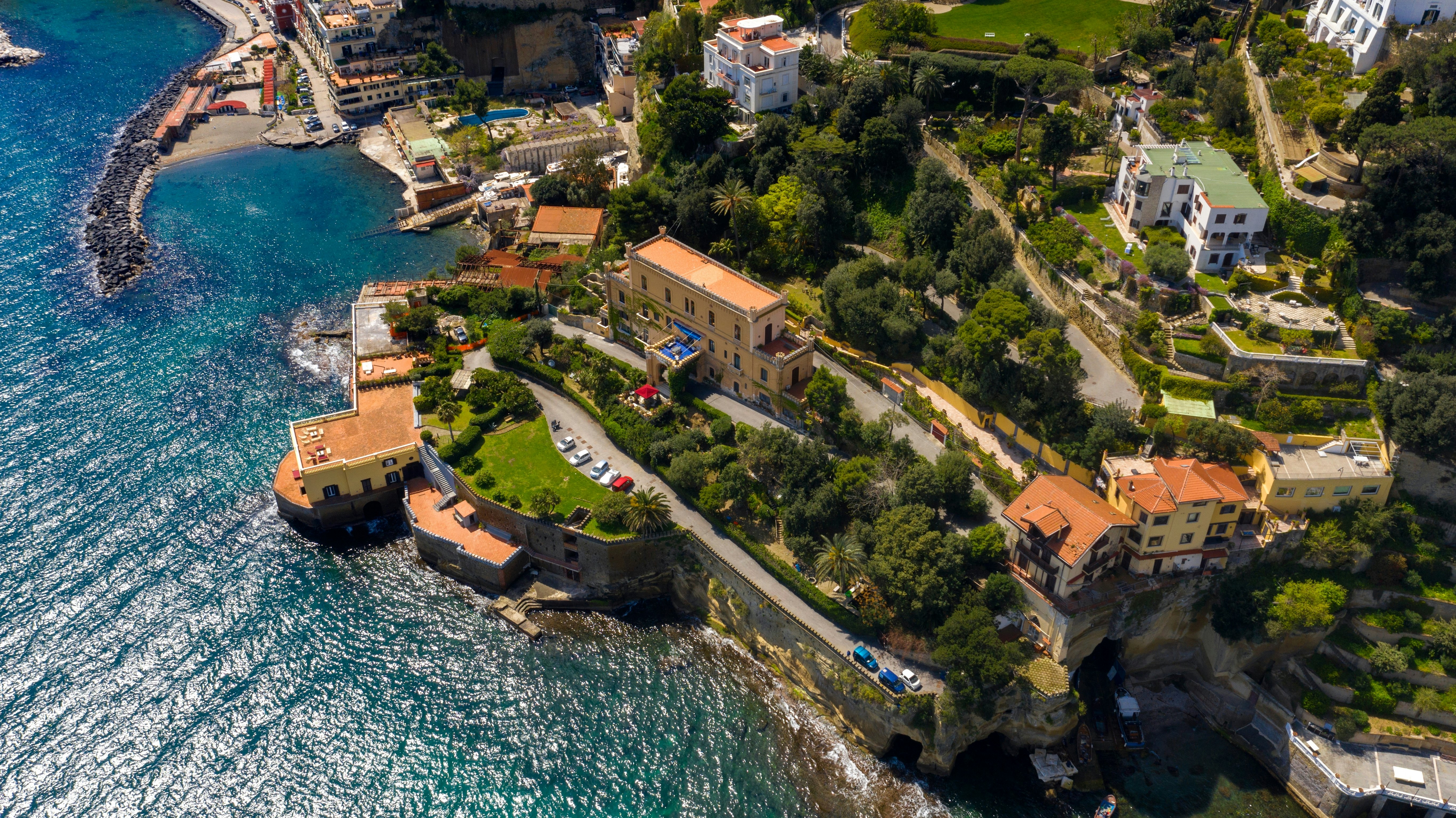 An aerial view of houses and windy roads on a cliff by the sea.