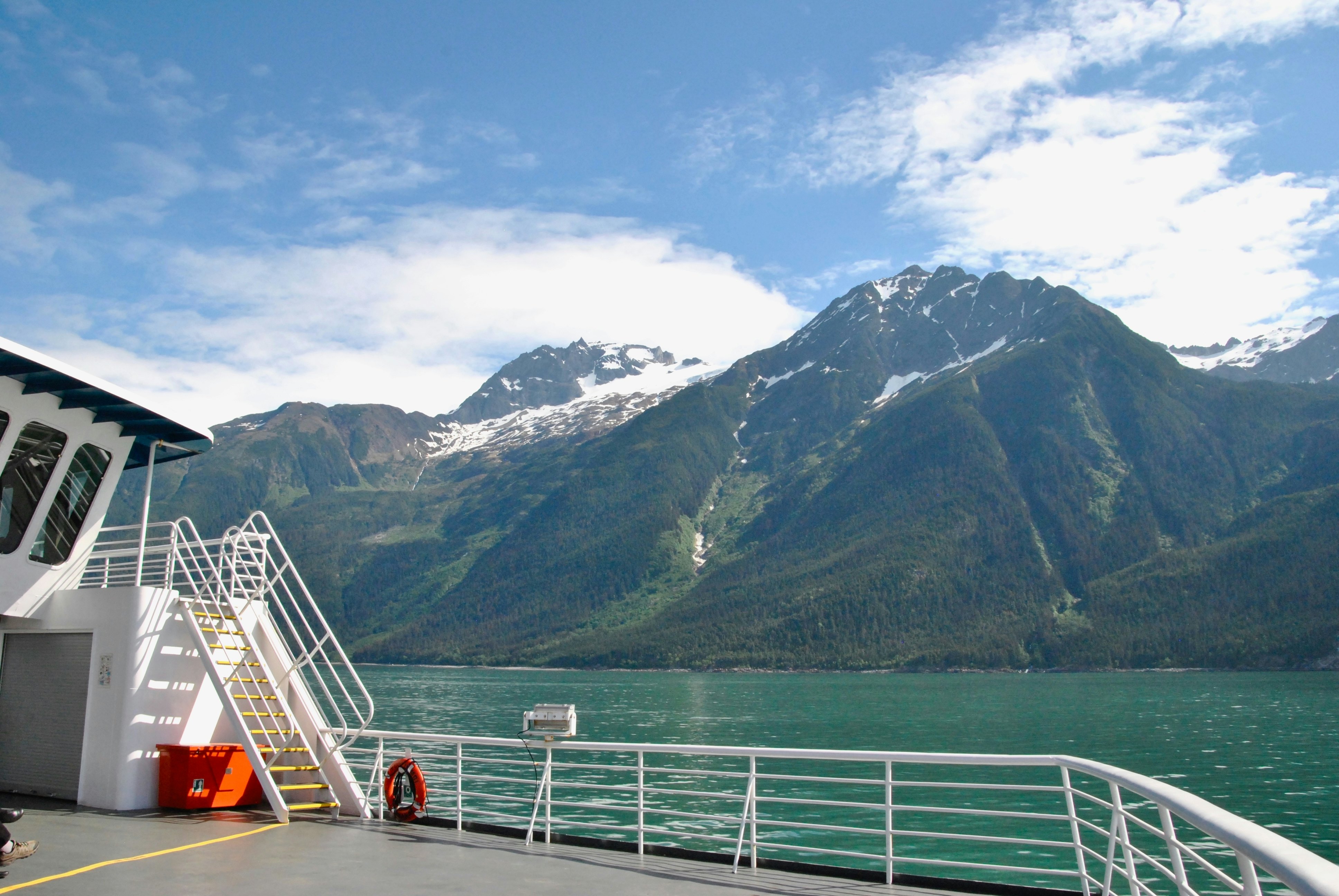 The view from over the side of an Alaskan Ferry looking at the water and mountains.