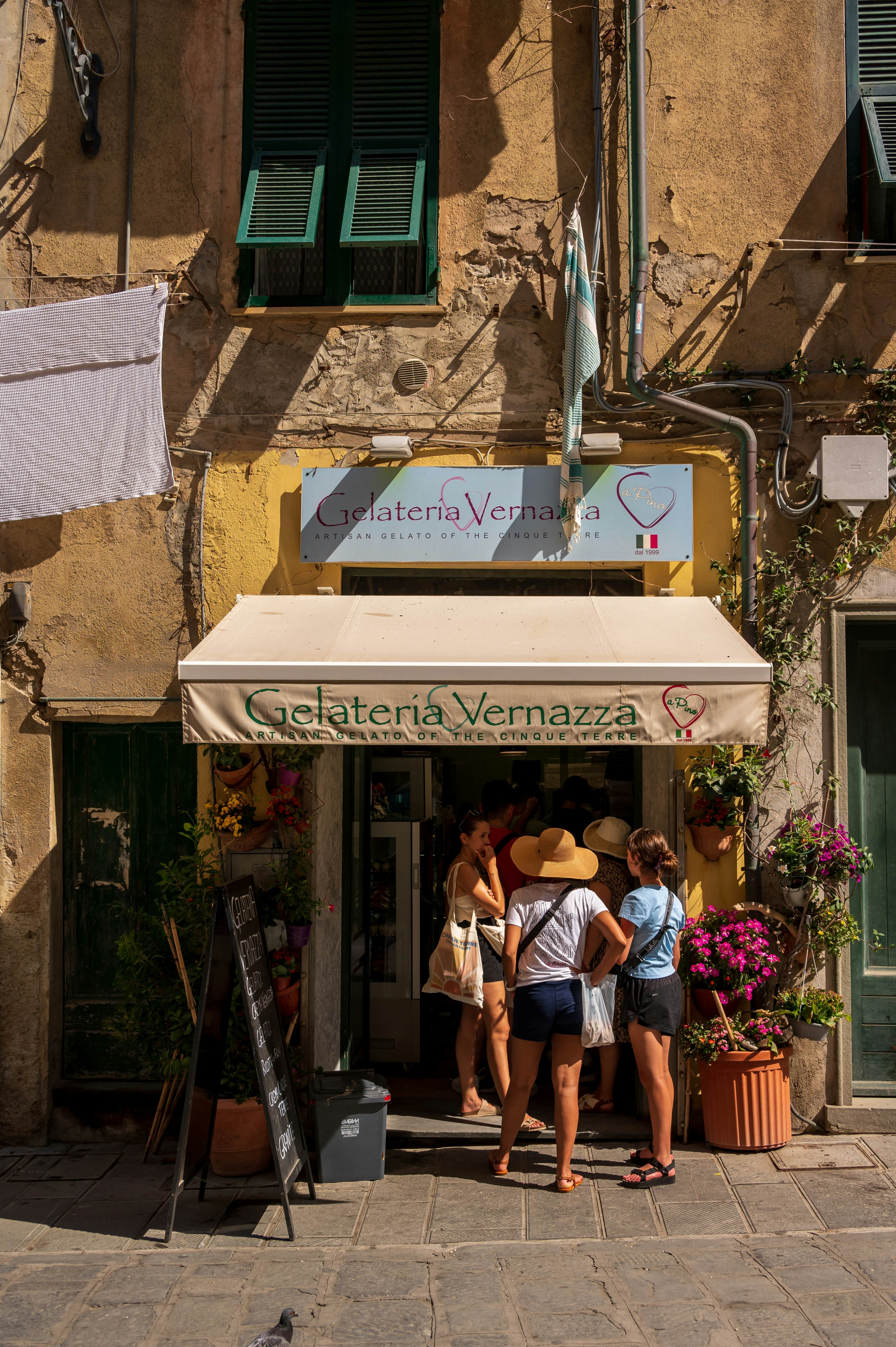 People in summer clothes queue outside an ice-cream shop in Vernazza.