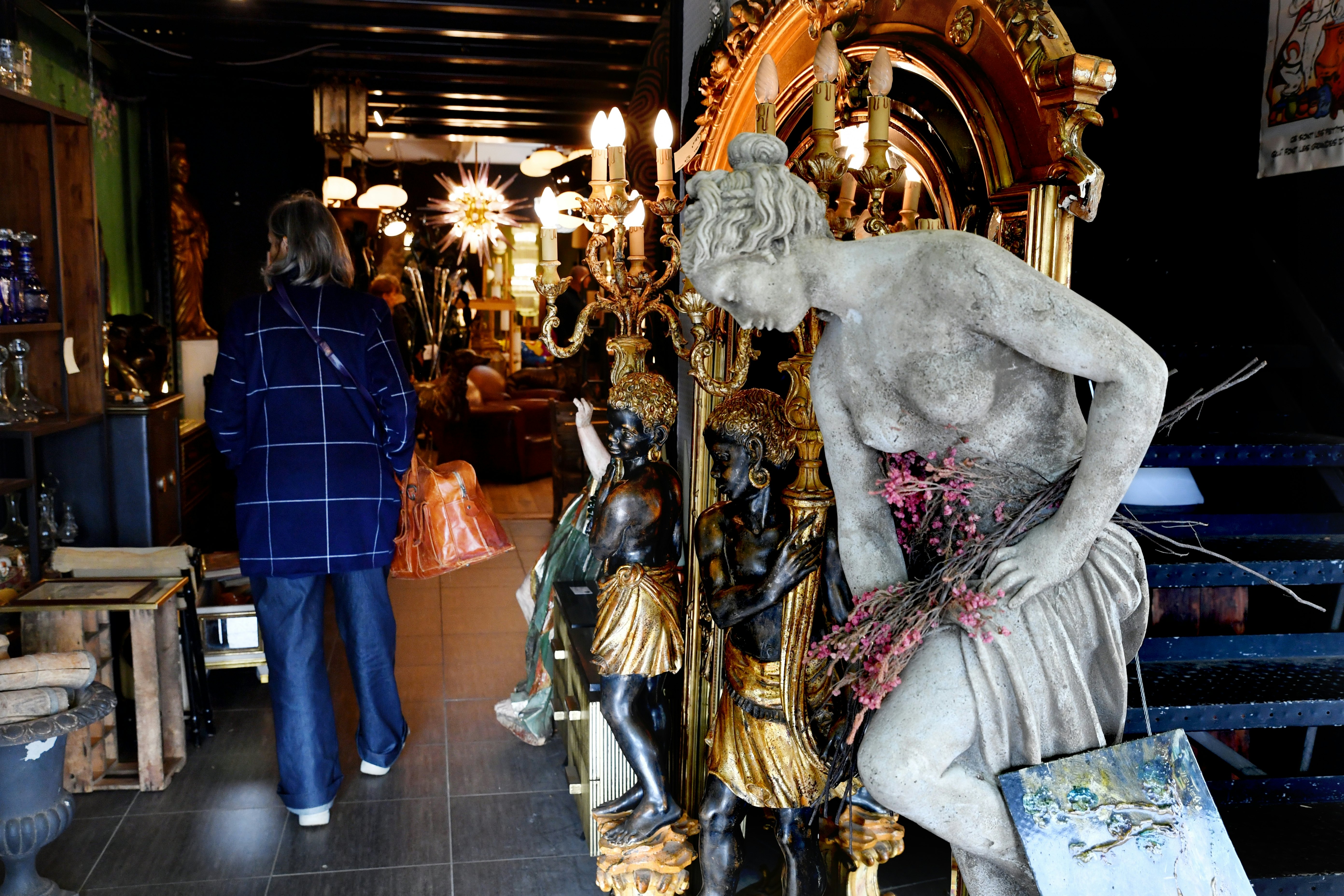 Statues, light fixtures and other antiques are for sale at a flea market.