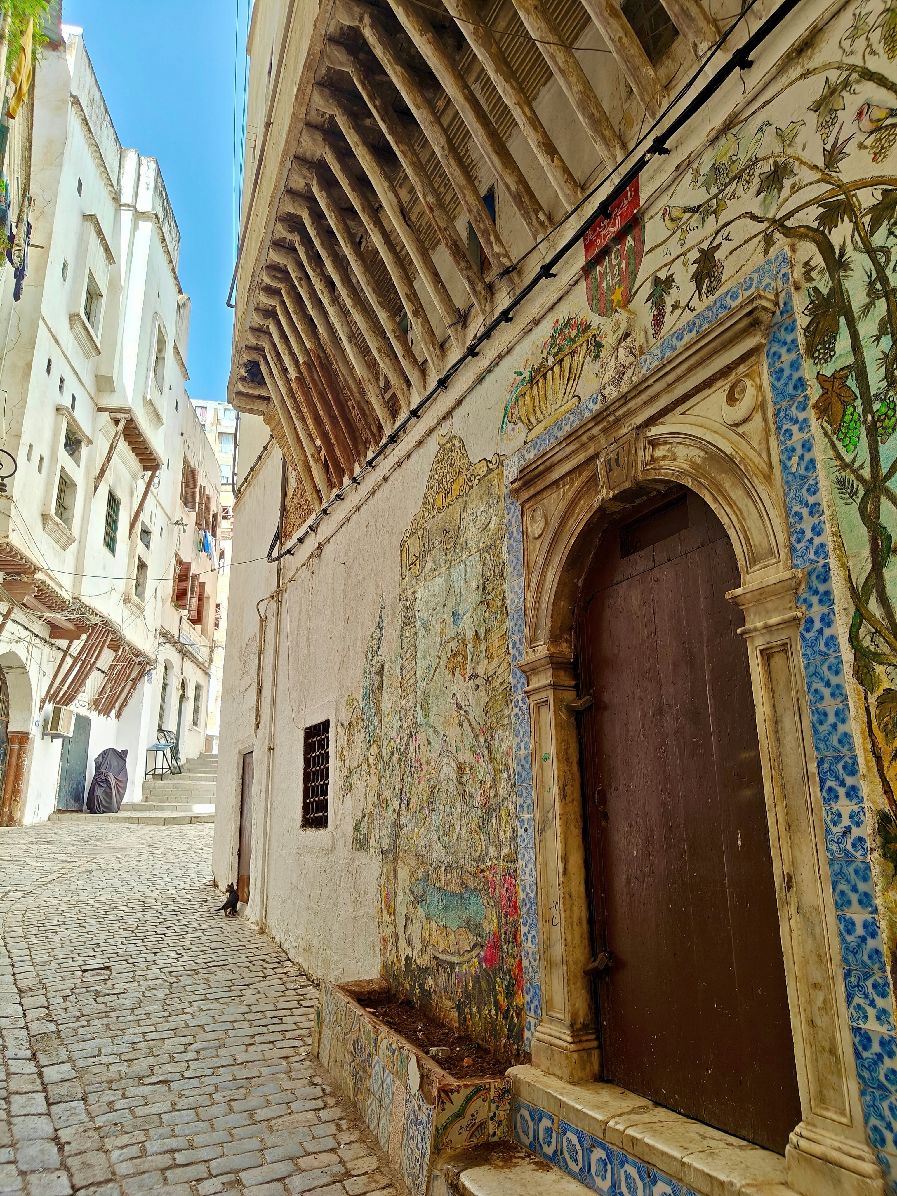 An ancient doorway surrounded by intricate tiles on a cobbled alley.