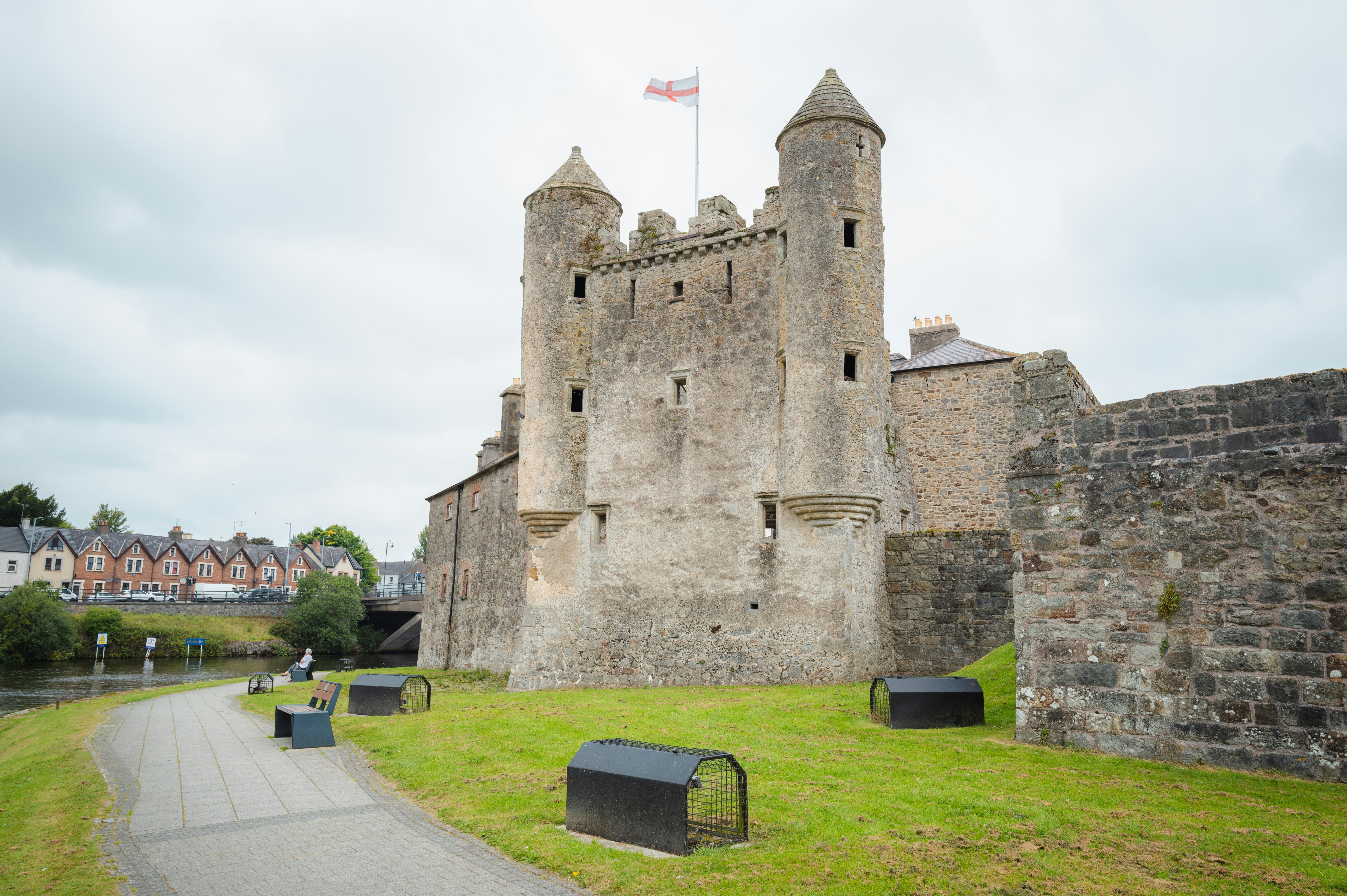 A gray castle with a stone path and closely trimmed grass around it.