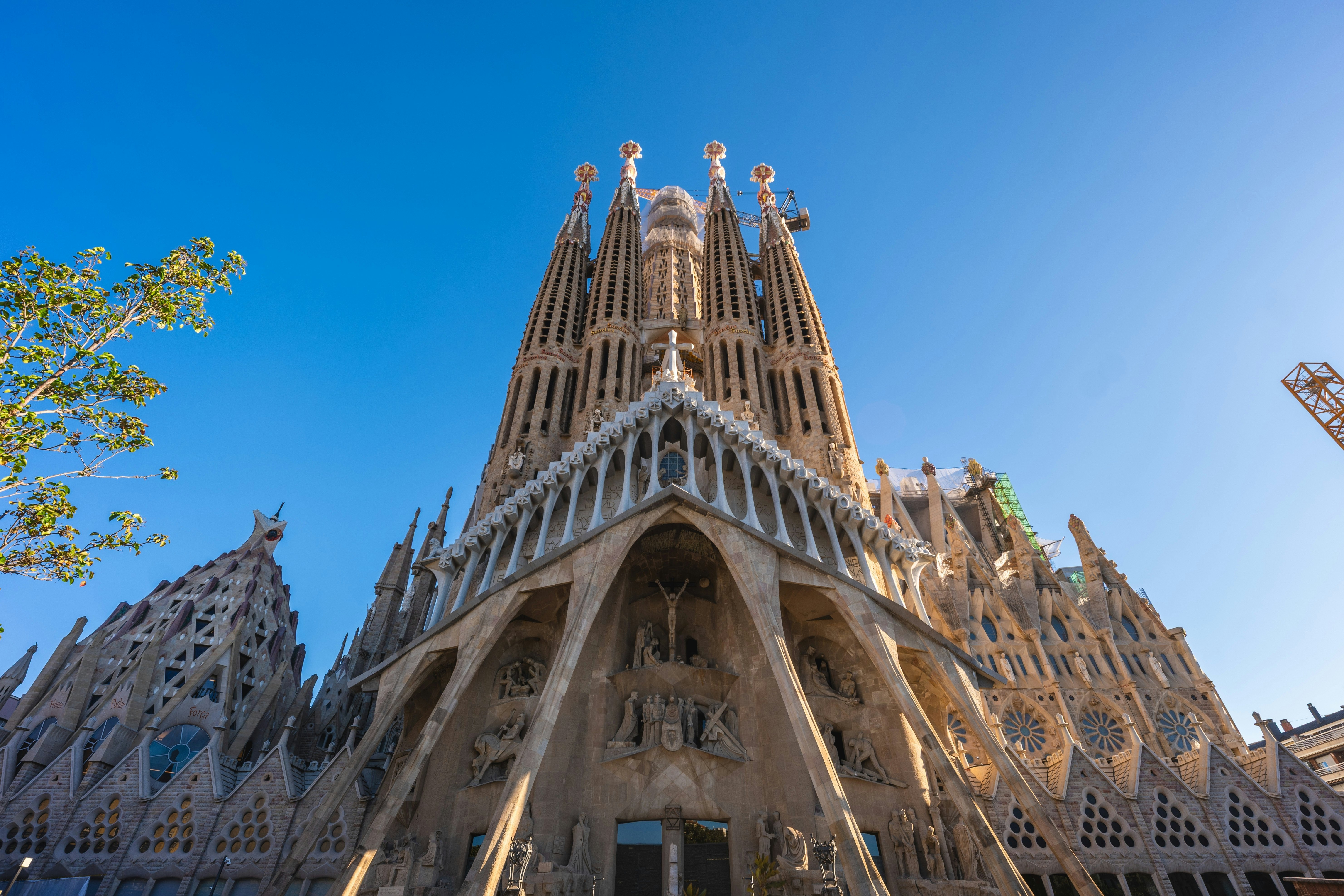 Elaborately carved stone spires of a church in Barcelona, Spain, against blue sky.