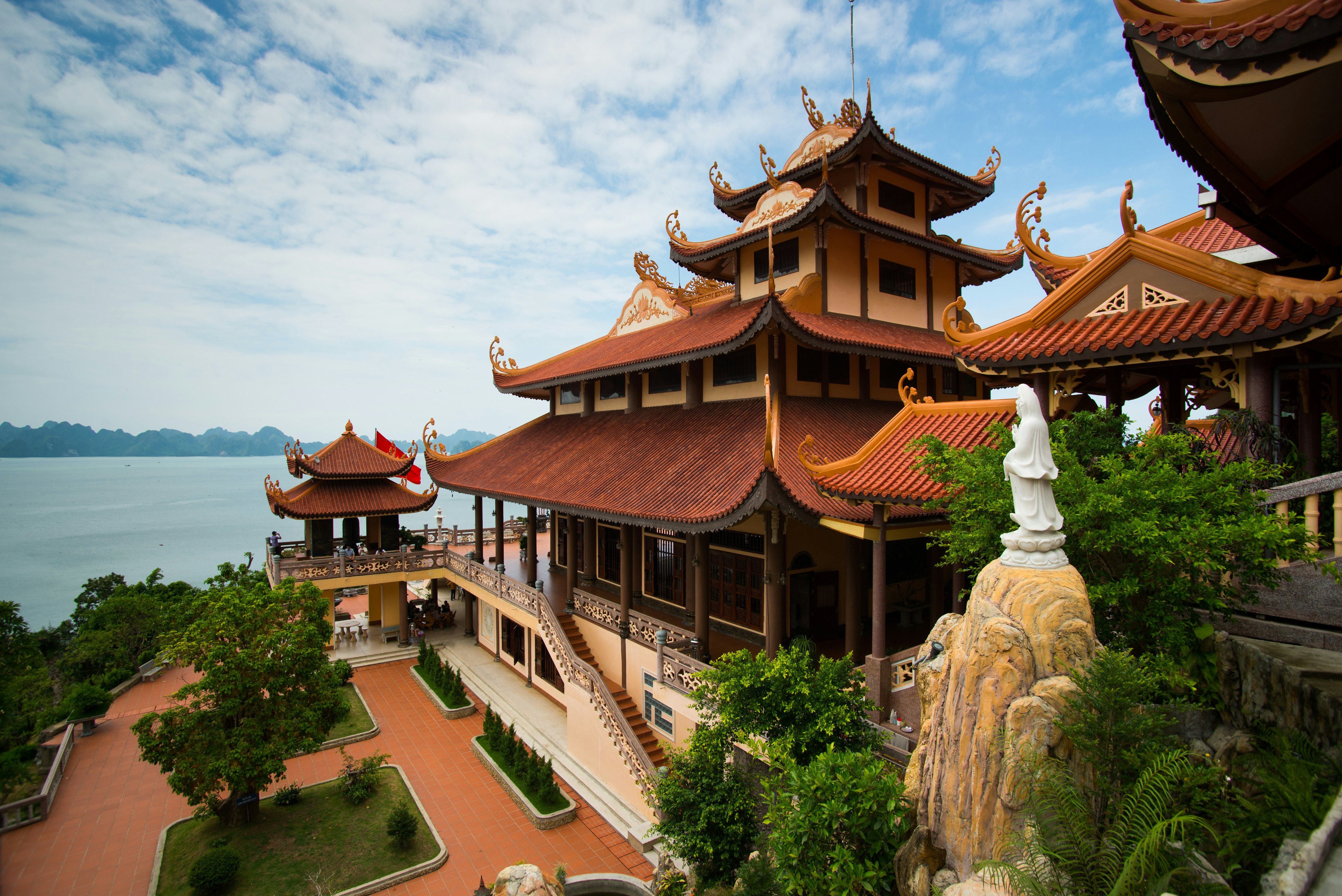The multilevel roofs of several structures at a temple complex by a bay in Vietnam.