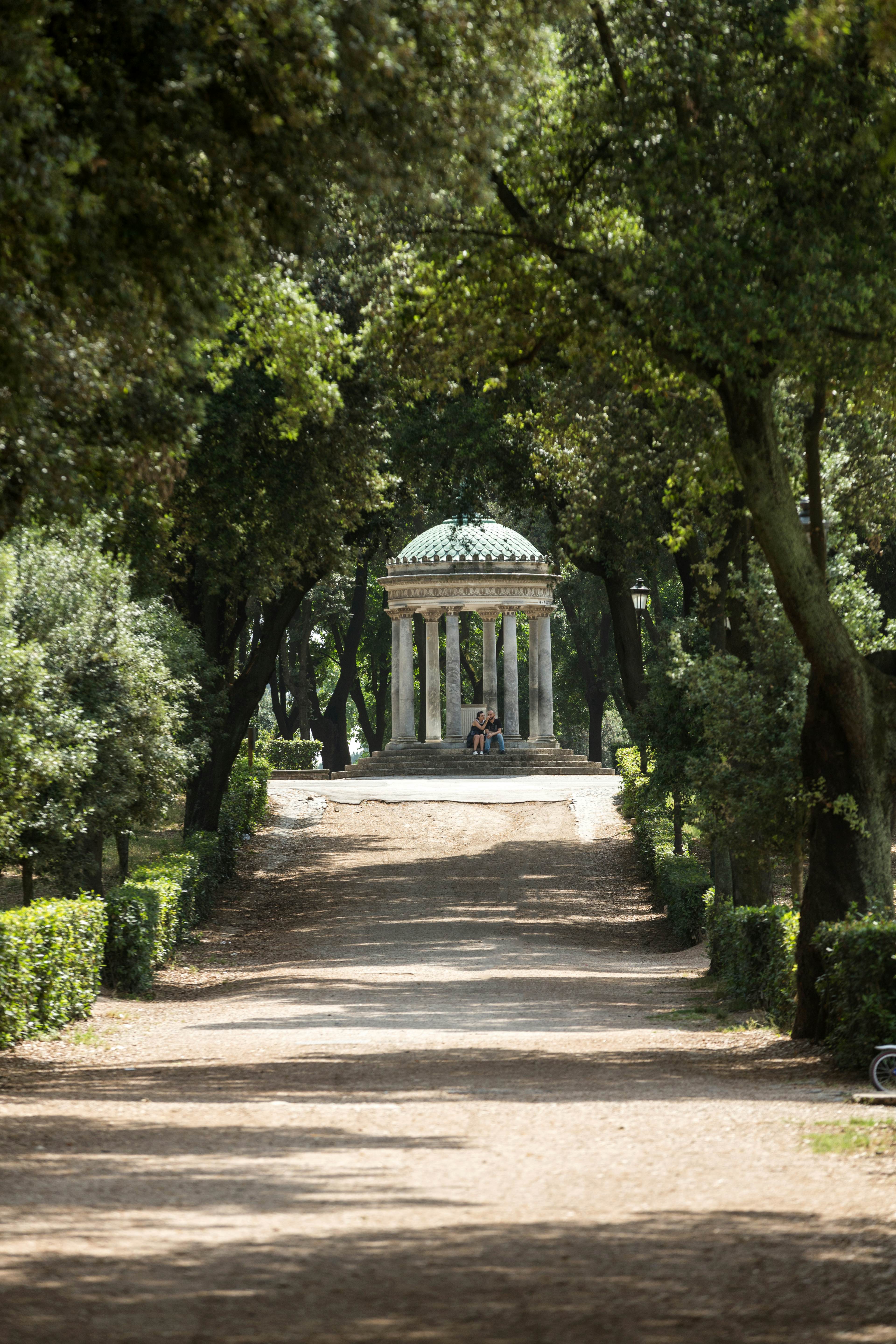 A neoclassical structure with eight Corinthian columns, surrounded by lush greenery.