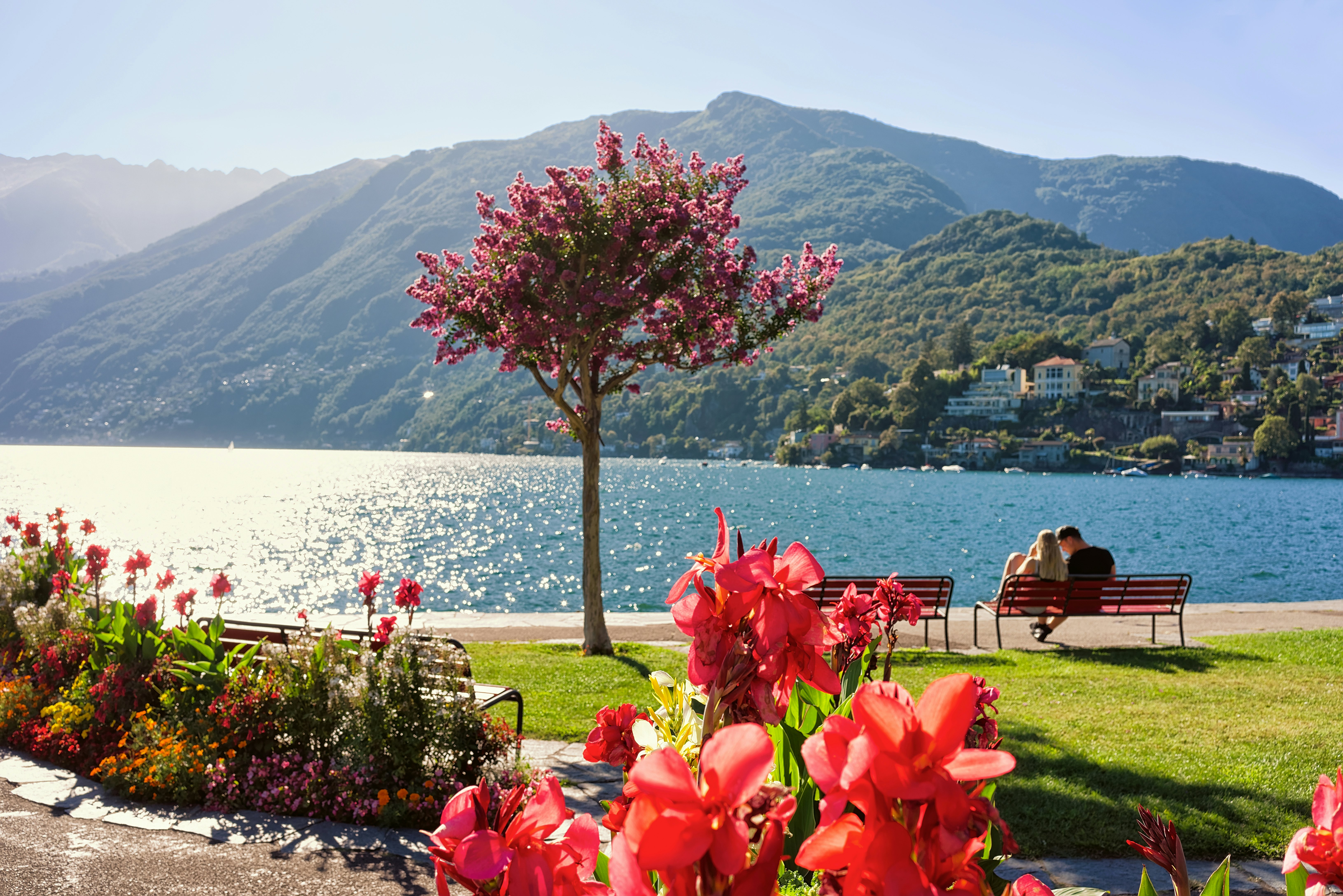Couple sitting on the bench at the promenade of the expensive resort in Ascona/ Locarno on Lake Maggiore, Ticino canton, Switzerland.