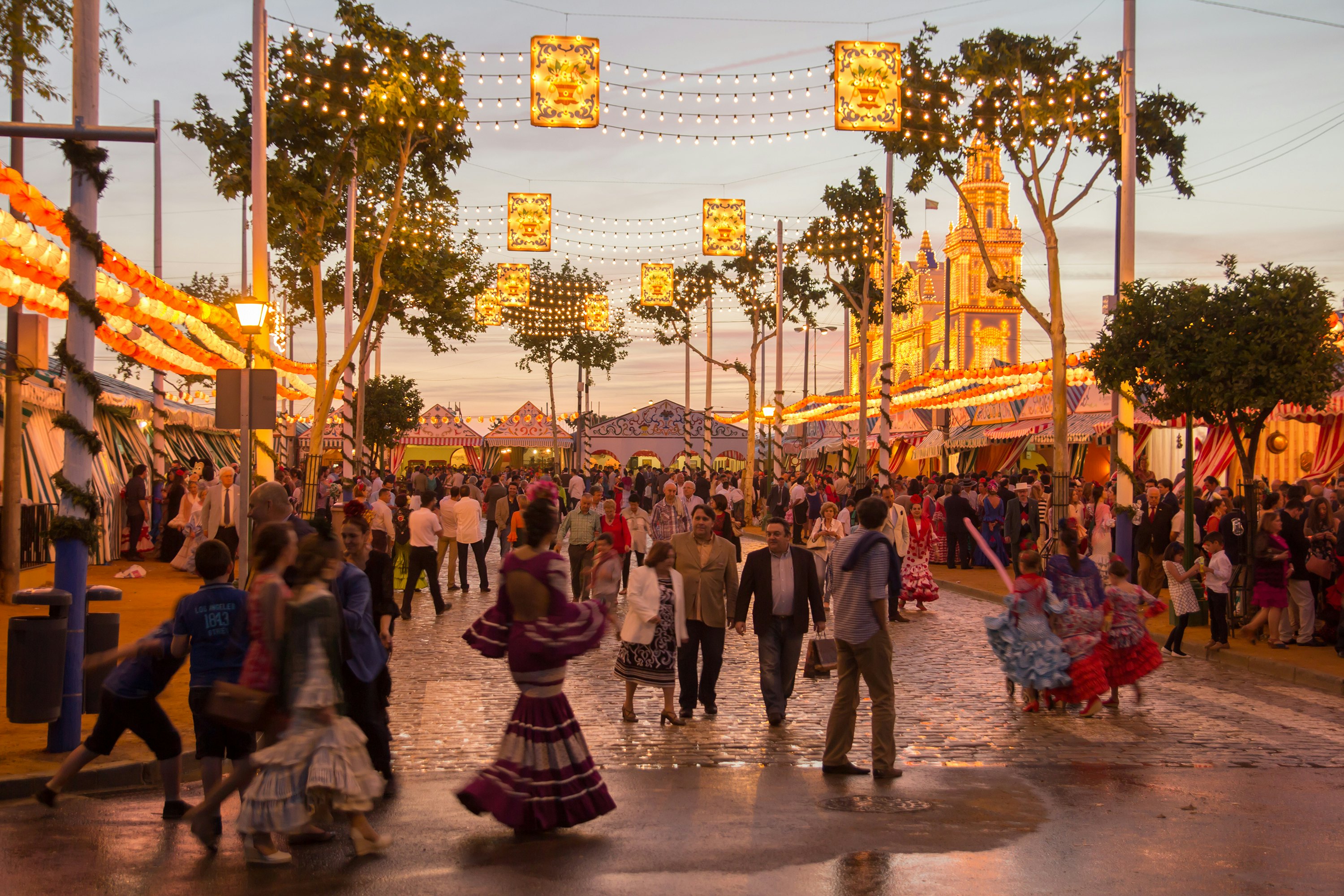 People walking on the sunset street and celebrating at the Seville's April Fair in Seville, Spain.