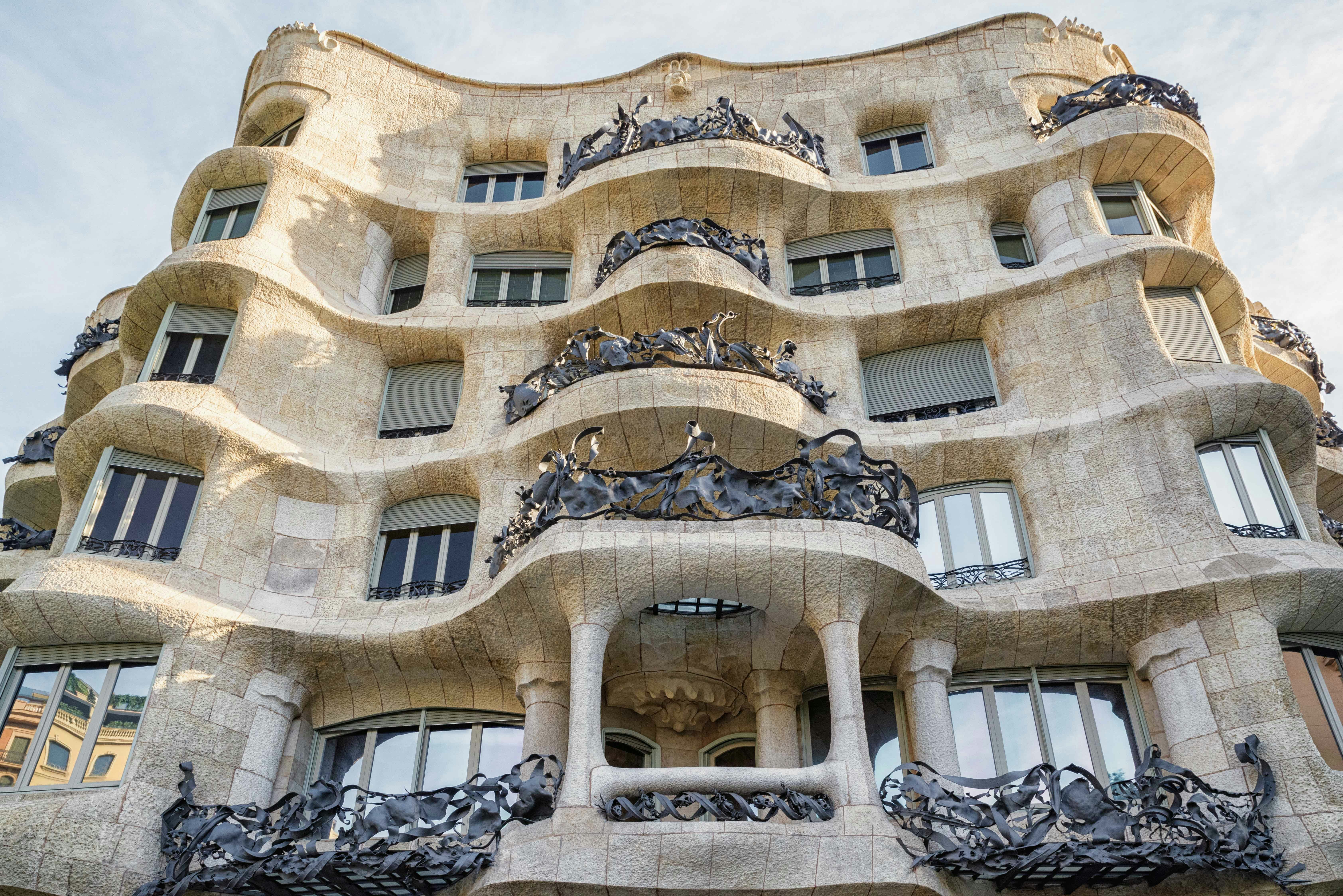 Elaborate iron railings on the balconies of a multilevel white stone building in Barcelona, Spain.