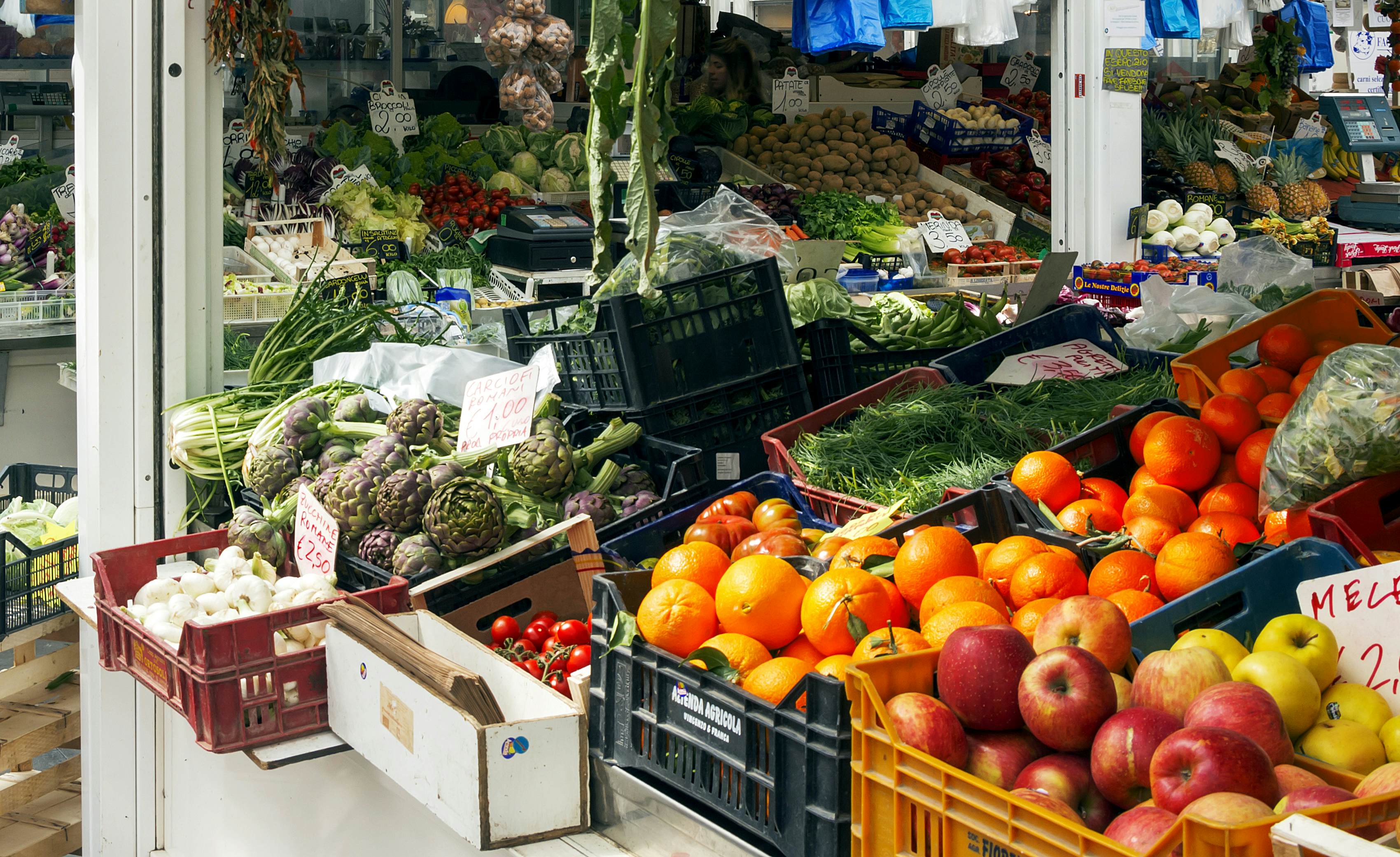 A greengrocer stall packed with fruit and vegetables at an indoor market