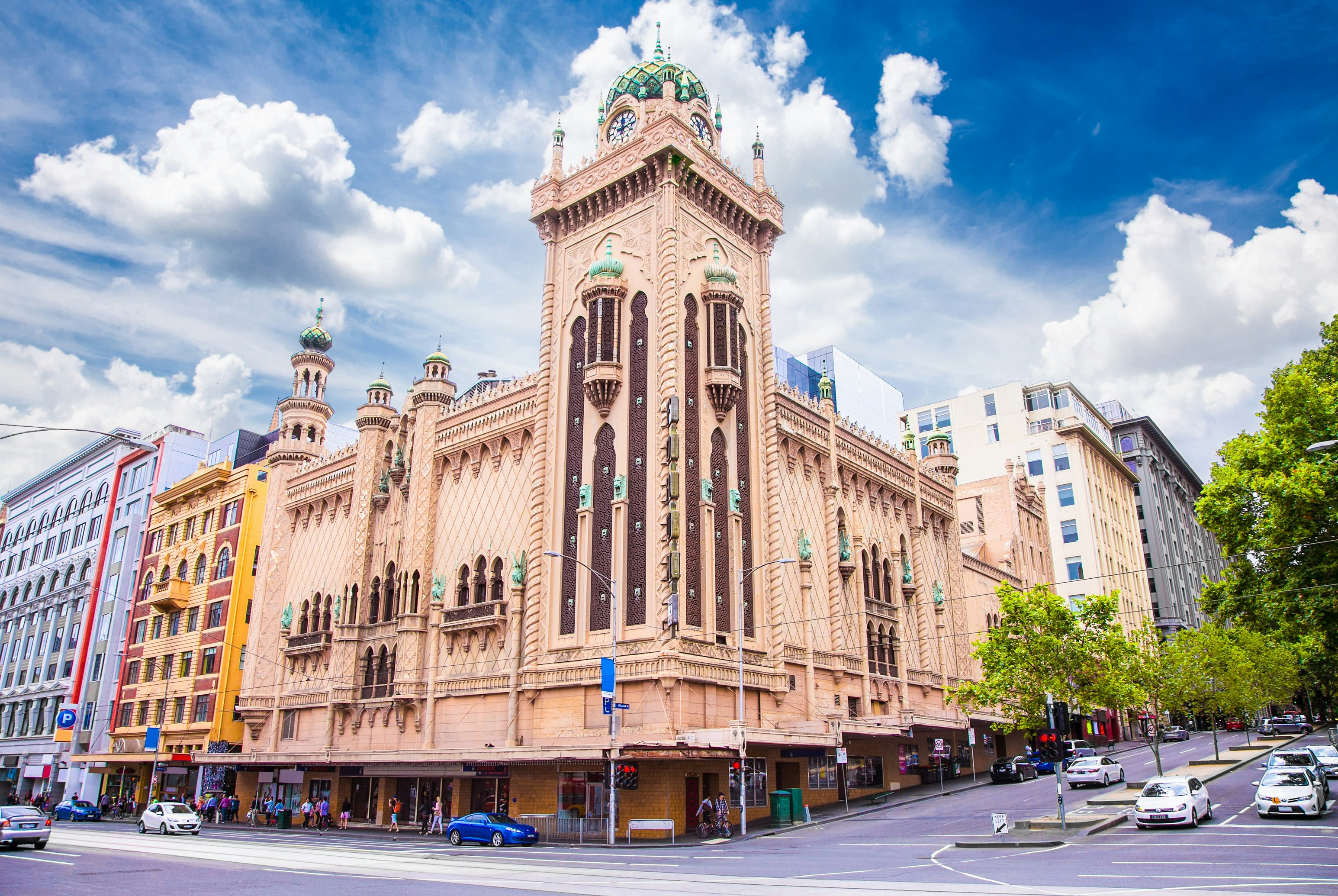 A theater building with a Moorish Revival-style exterior at the corner of a busy road intersection in a city.