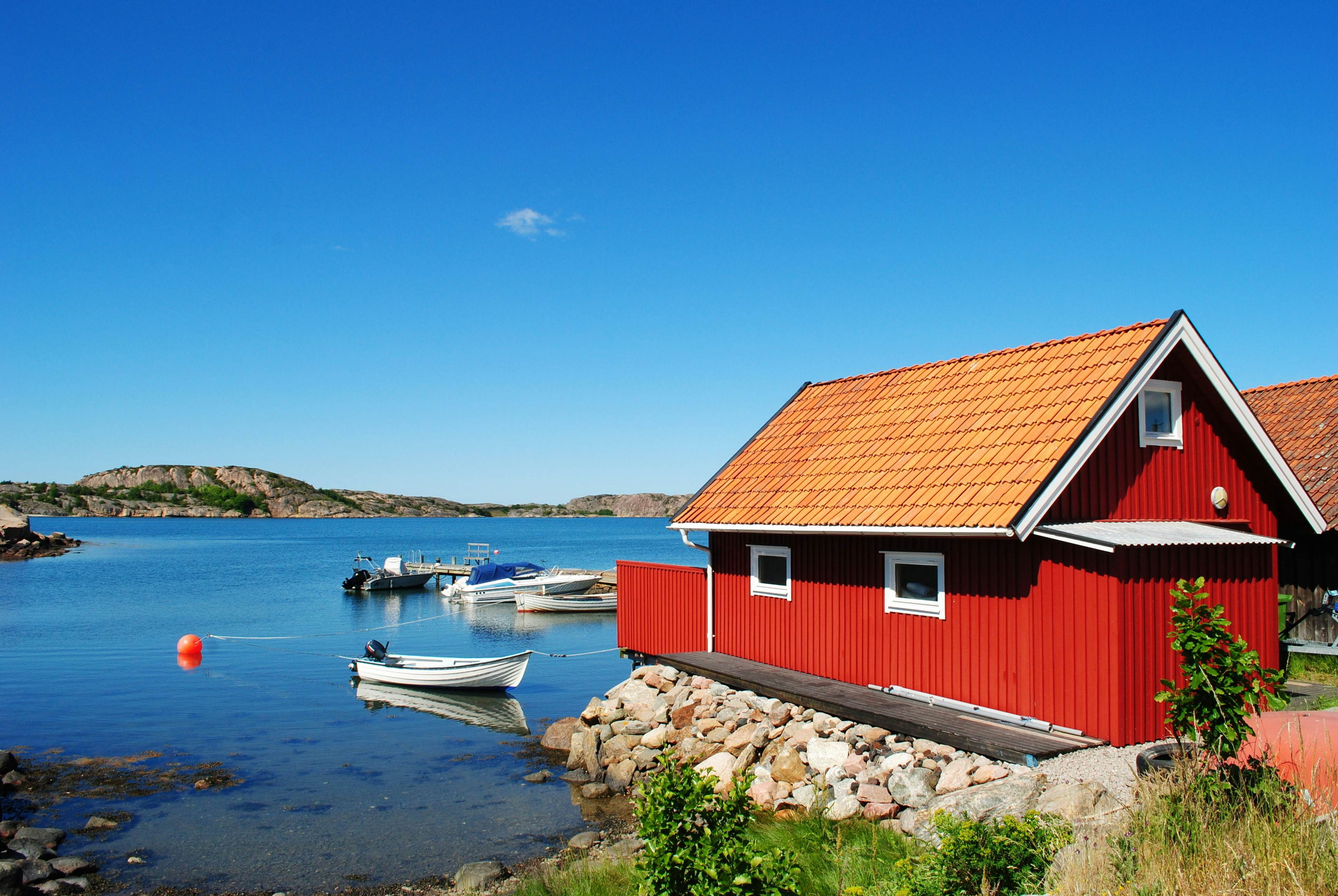 A red boat hut with skiffs on the water nearby in Marstrand Sweden.