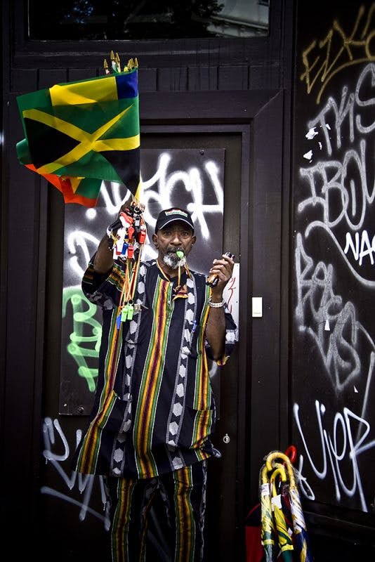 Notting Hill Carnival festival man waves a flag and blows a whistle