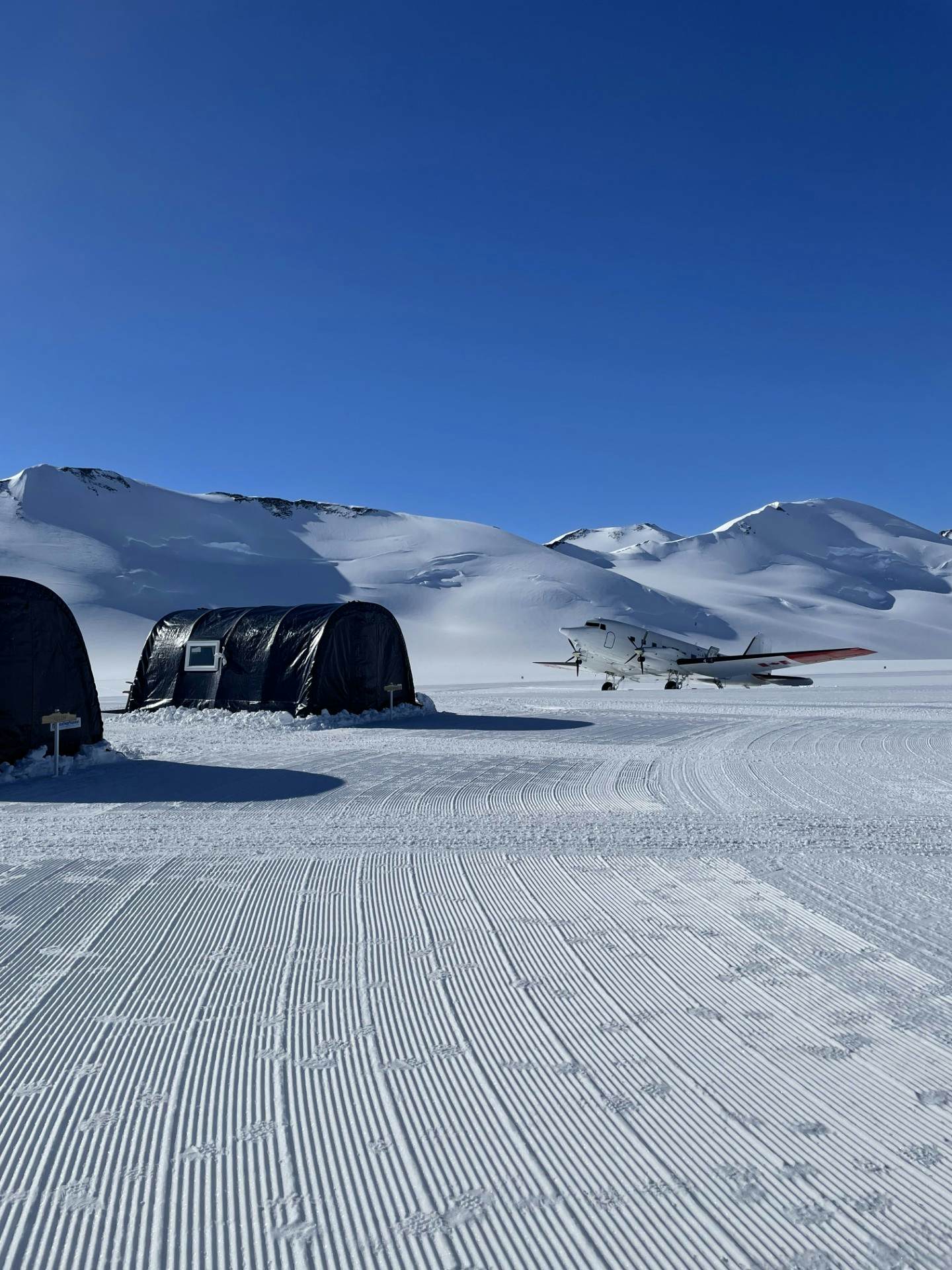 A small plane near a row of tents in snow
