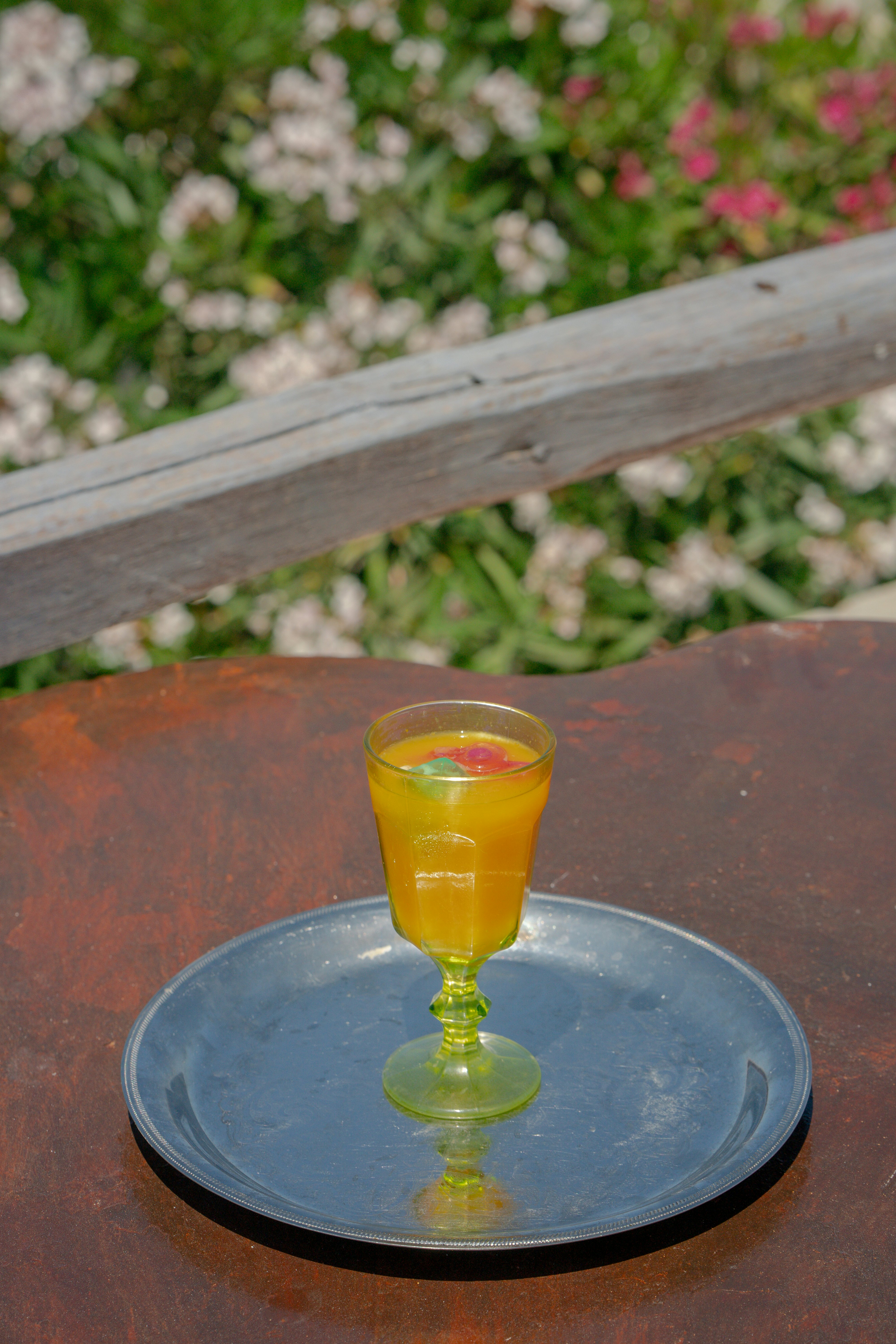 Orange juice in a translucent green goblet on a silver tray