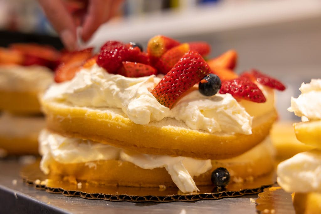 A close-up shot of cake topped with whipped cream and berries.