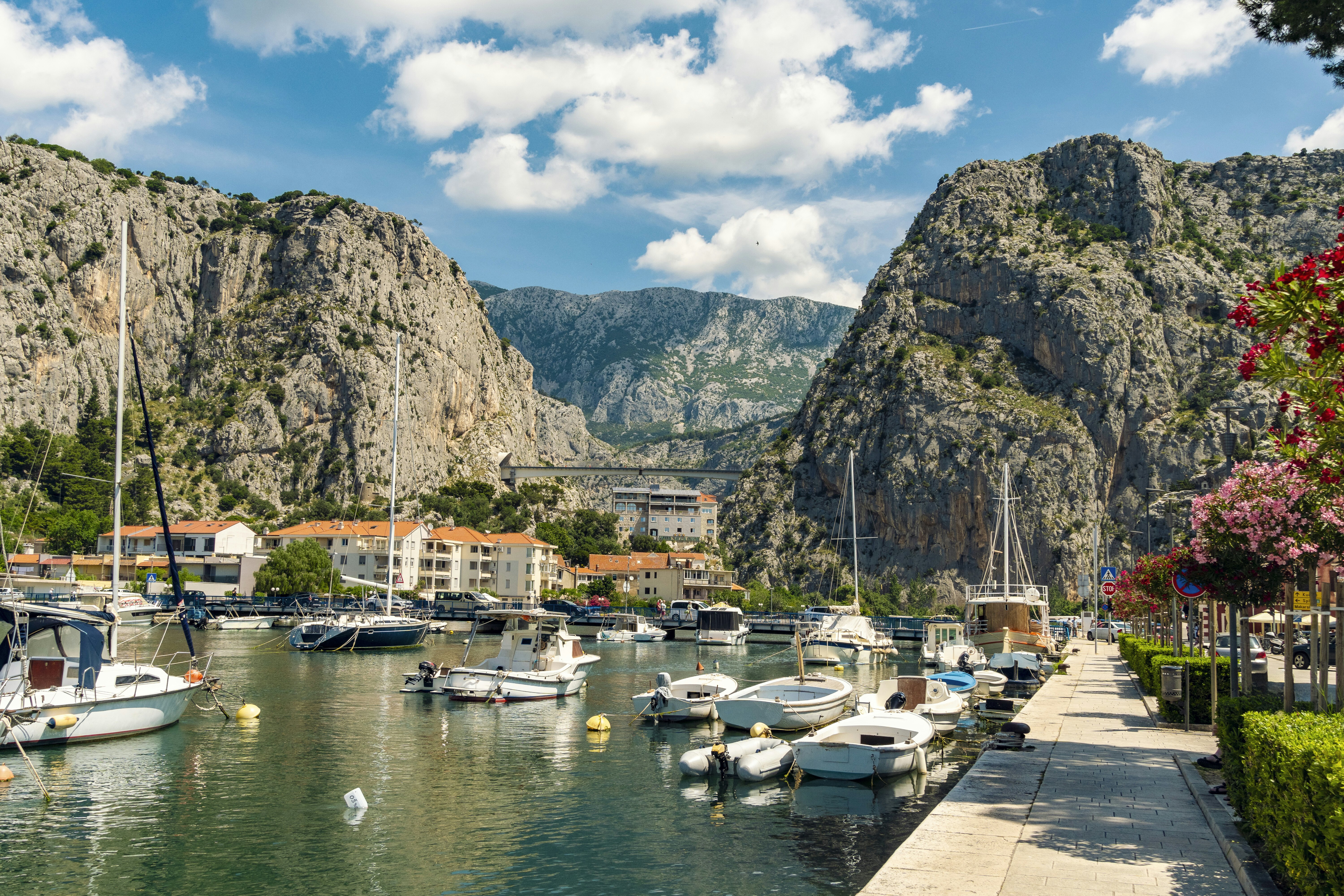 Dramatic granite cliffs frame a small harbor in a coastal town bathed in sunshine.