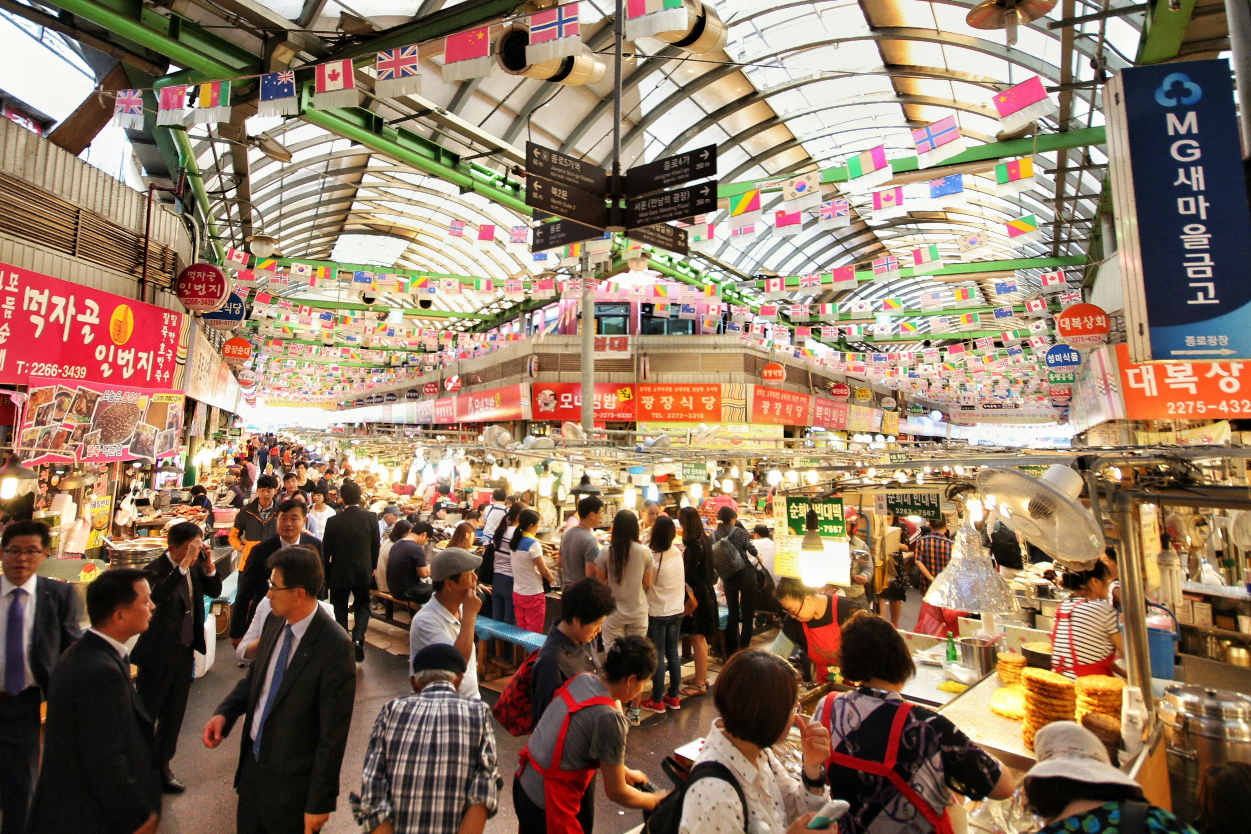 A wide shot of hundreds of people visiting the stalls of a huge, covered food market.