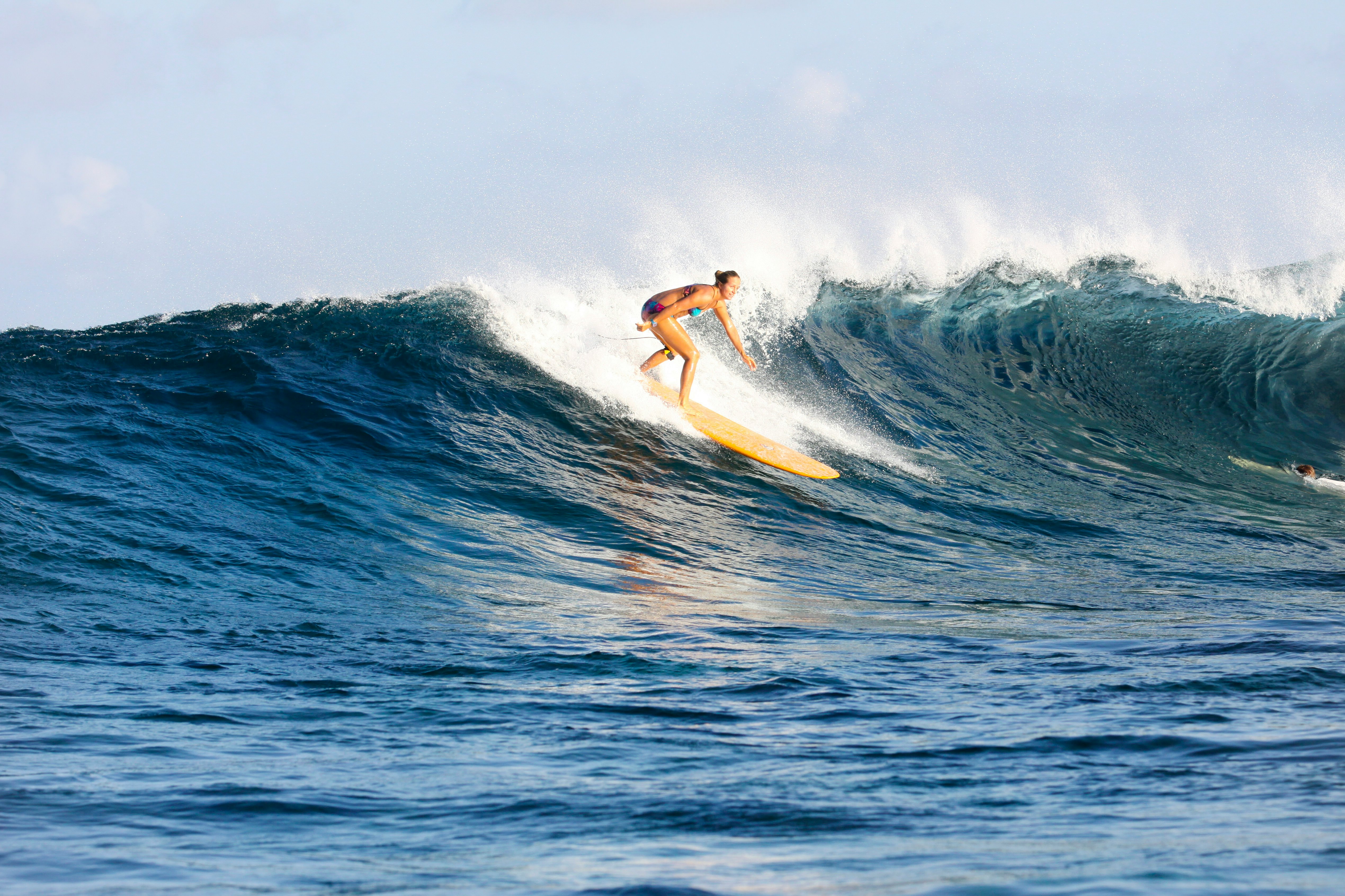 A surfer on a yellow board rides a crashing wave in the Maldives.