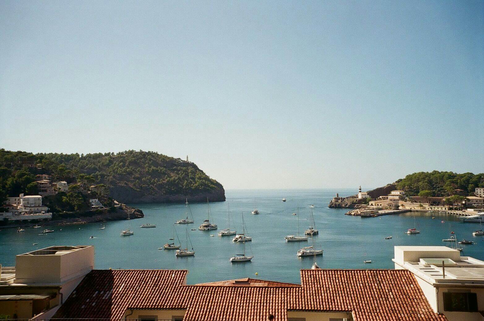 Boats in a harbor; red tiled roofs are in the foreground.