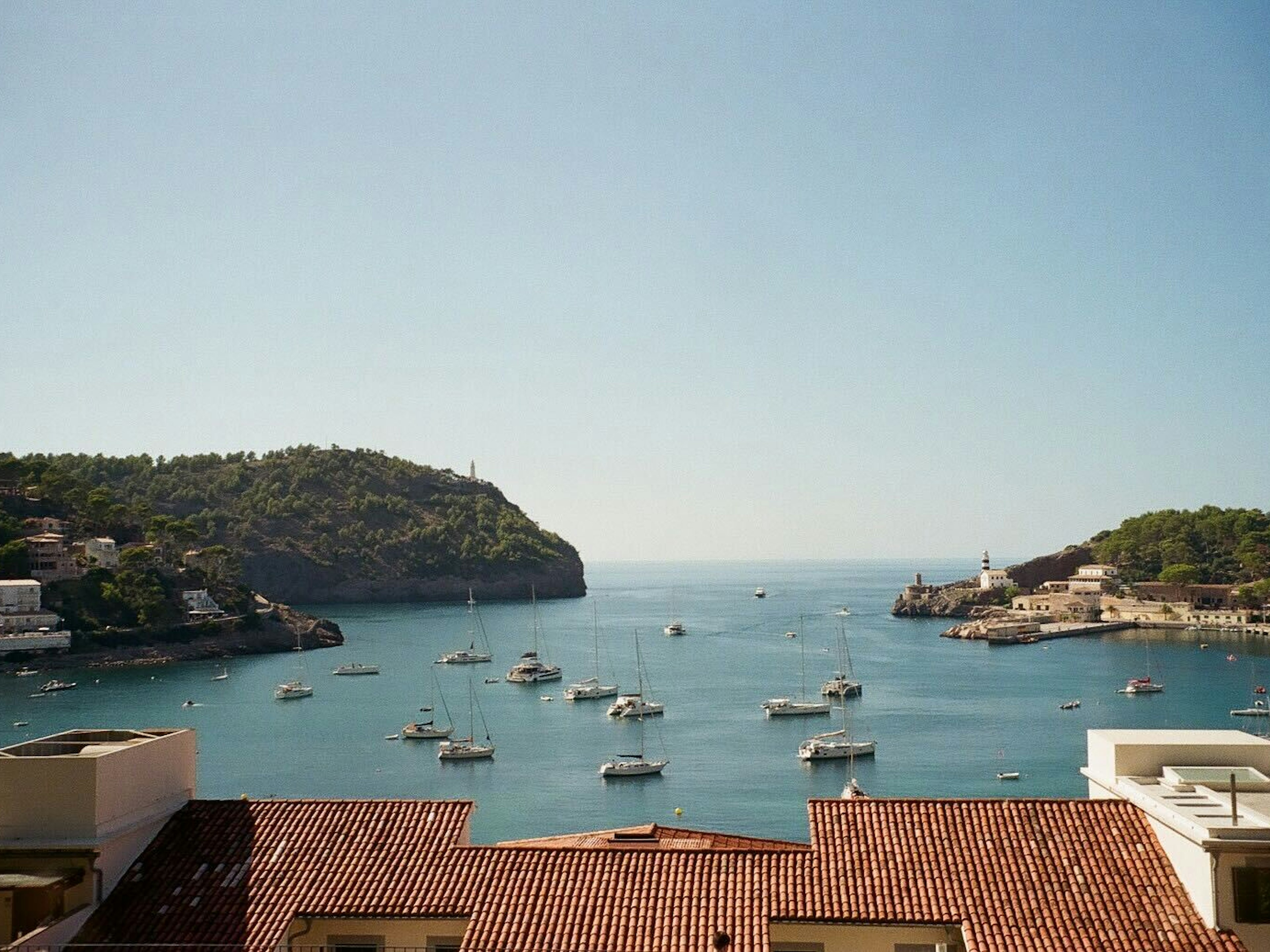 Boats in a harbor; red tiled roofs are in the foreground.