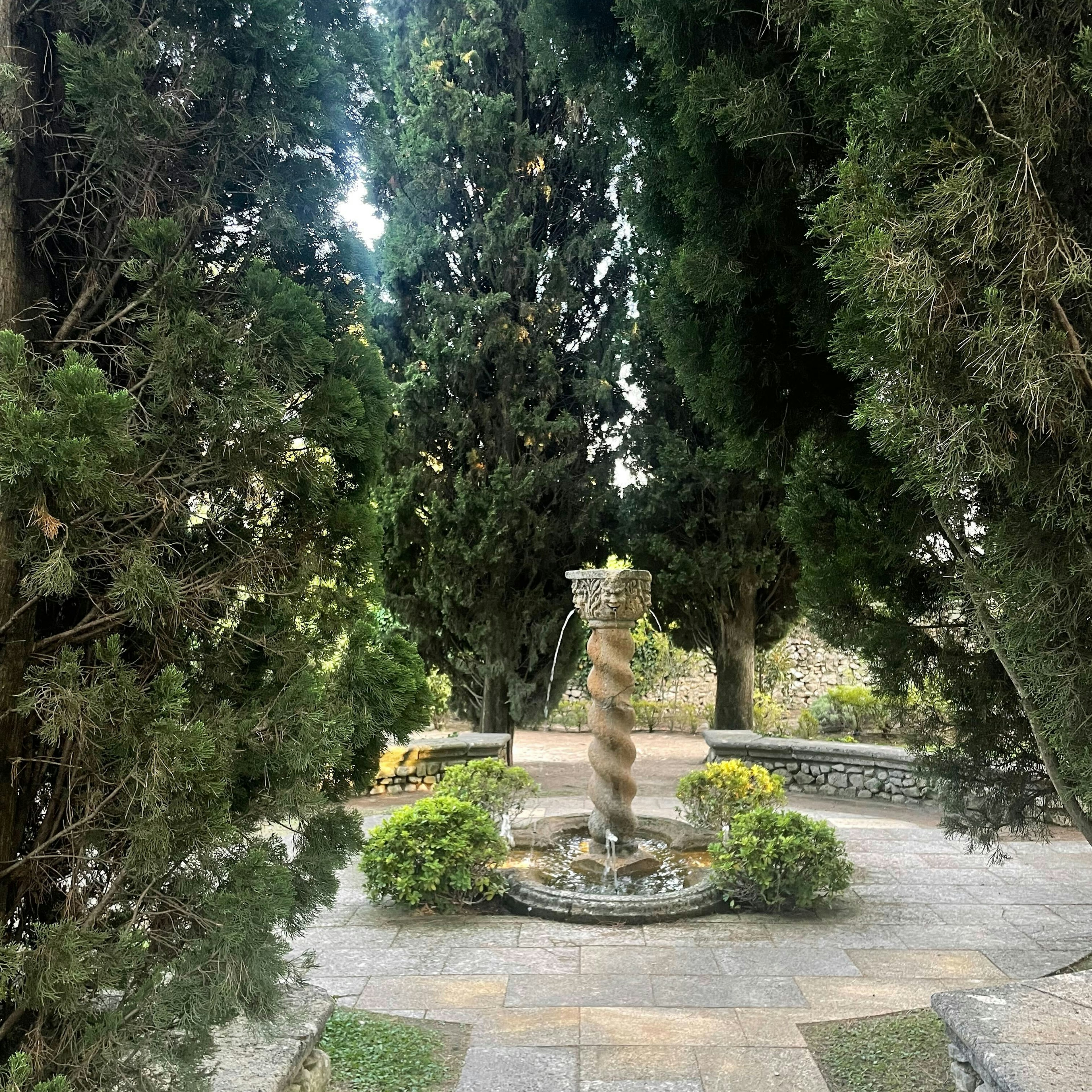A fountain in the center of a patio in a garden.