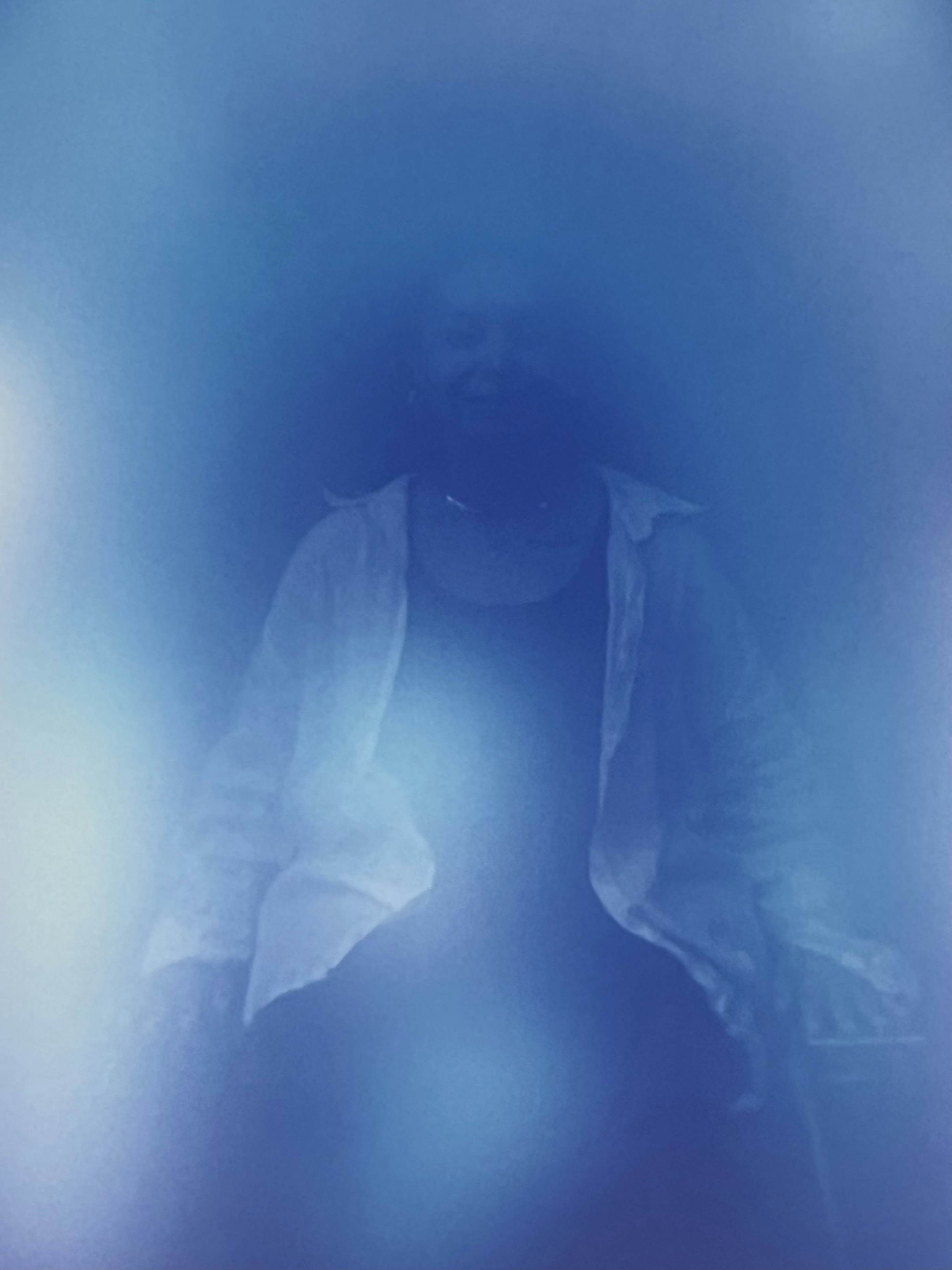 A seated person in blue light.