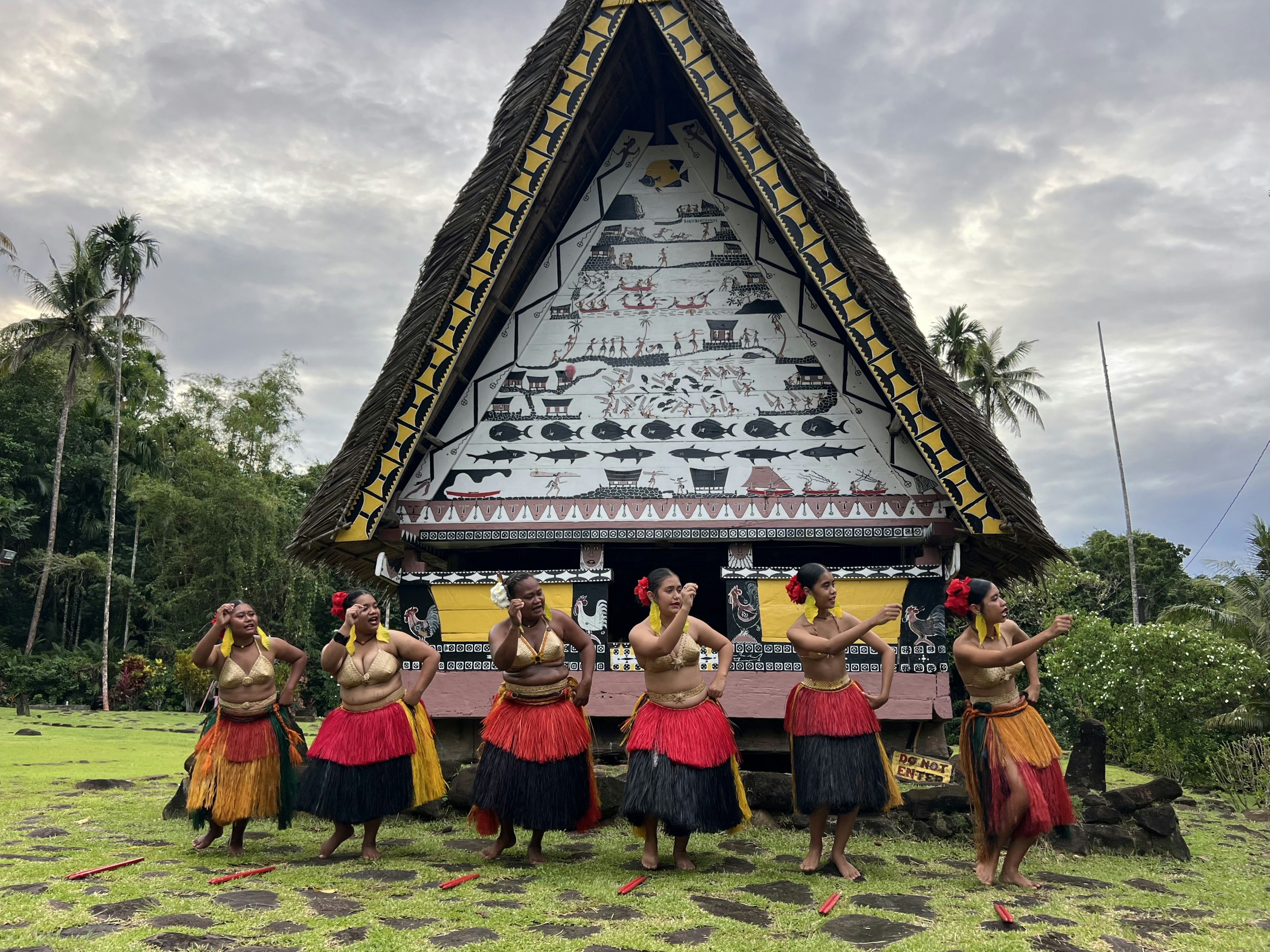 Women in grass skirts perform a traditional dance in front of the bai in Airai, Palau.