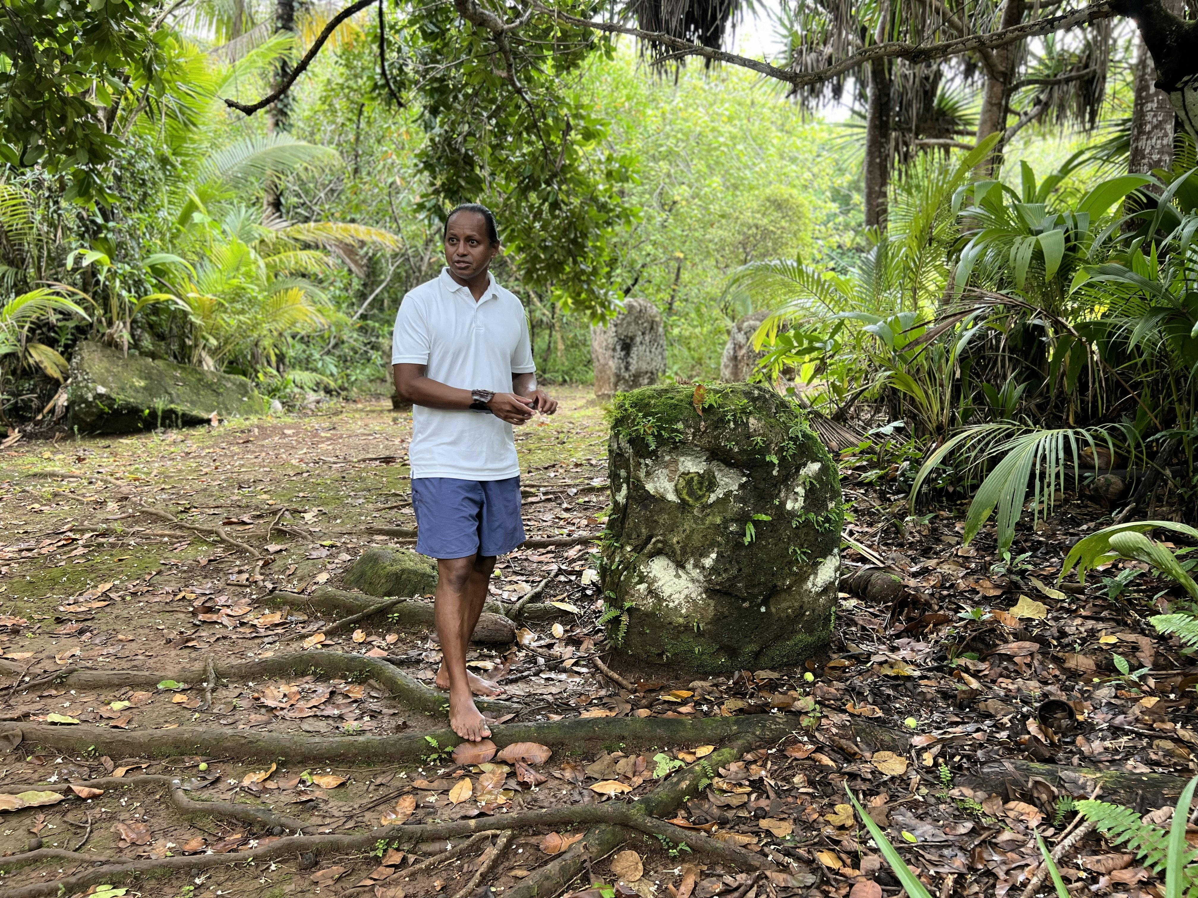 A guide stands beside a stone pillar, one of the Badrulchau monoliths in Palau.