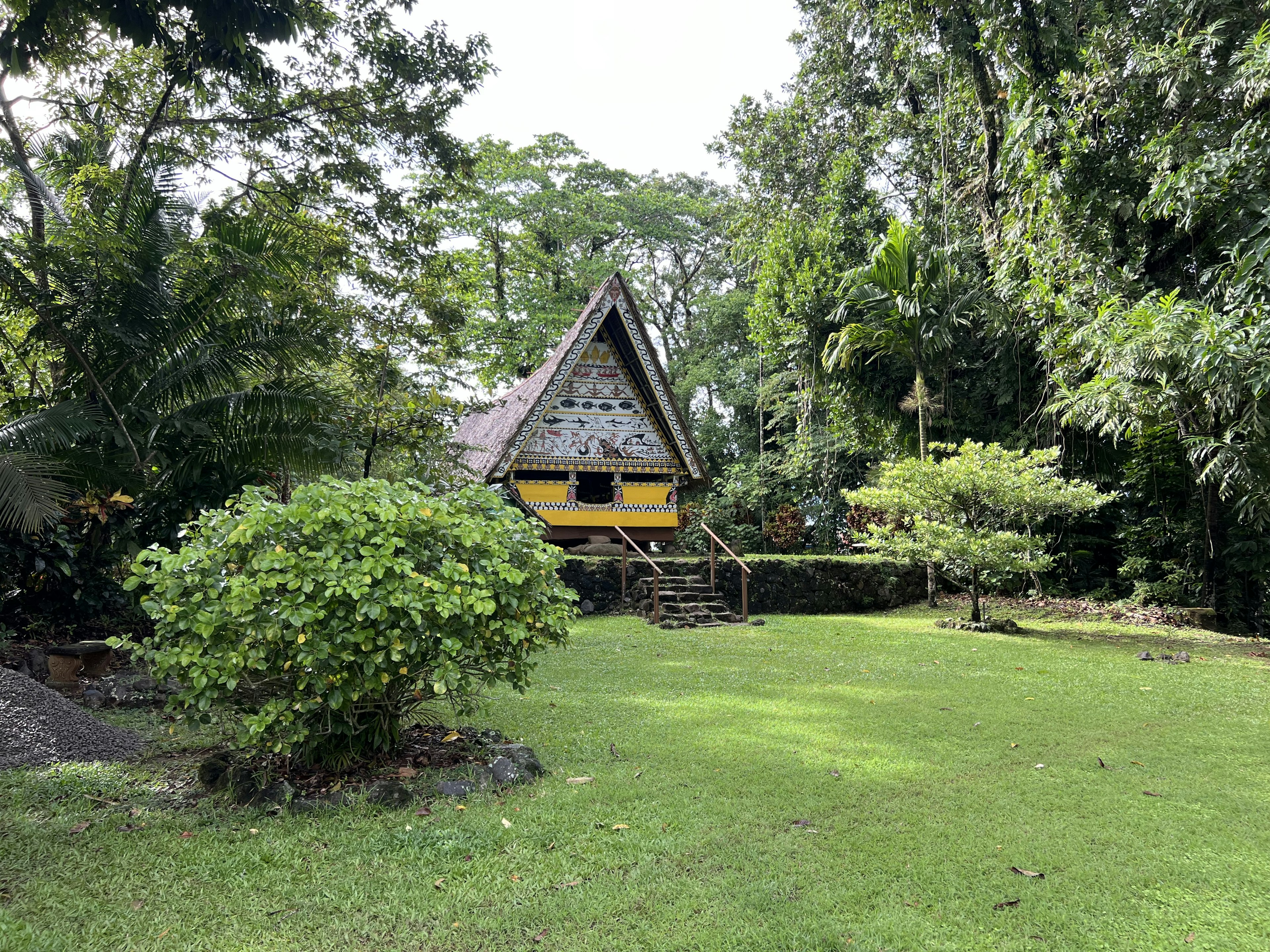 A restored bai meeting house at the Belau National Museum in Palau, surrounded by green gardens.