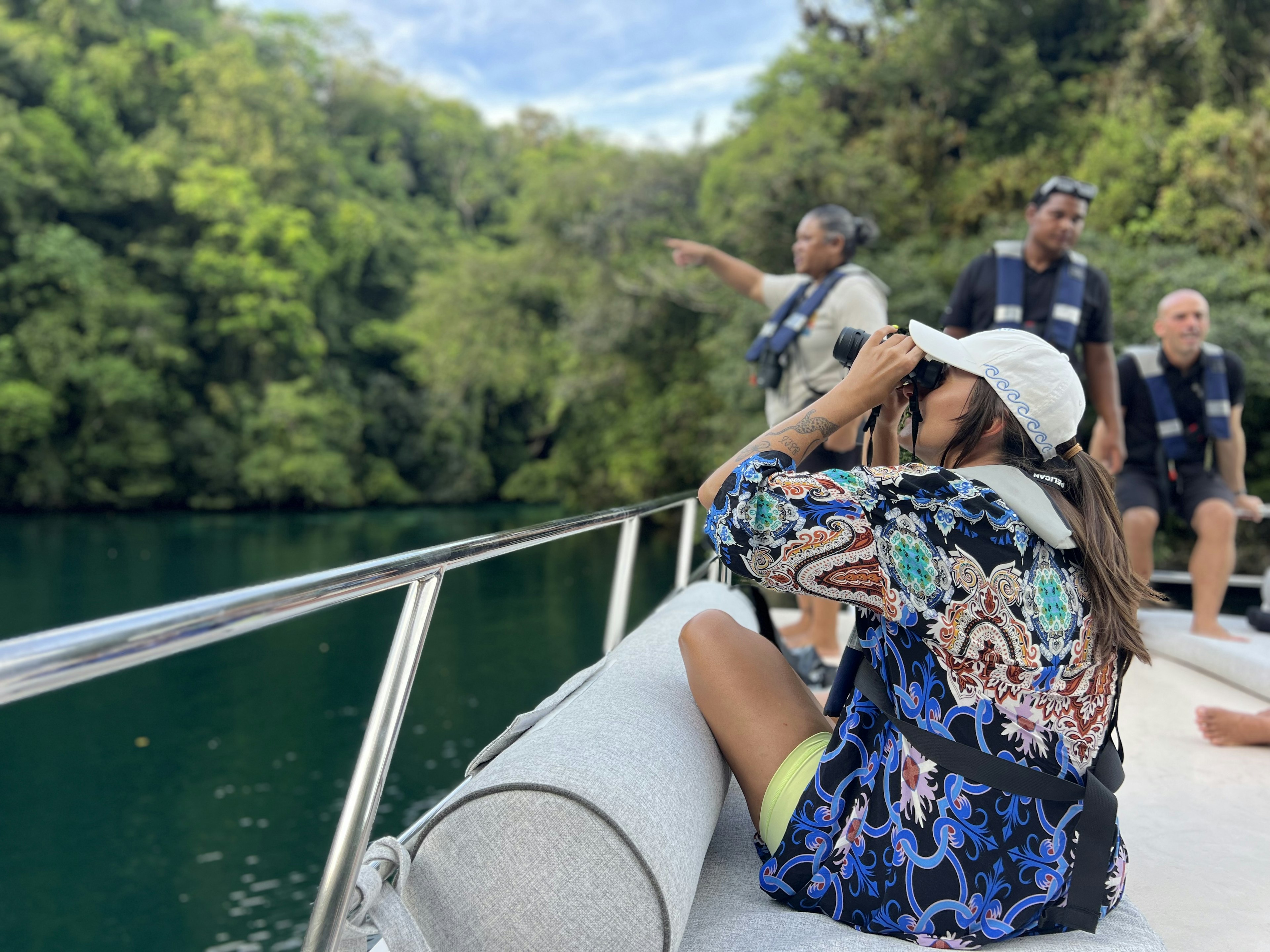 A woman with binoculars birdwatching from a boat in Palau.