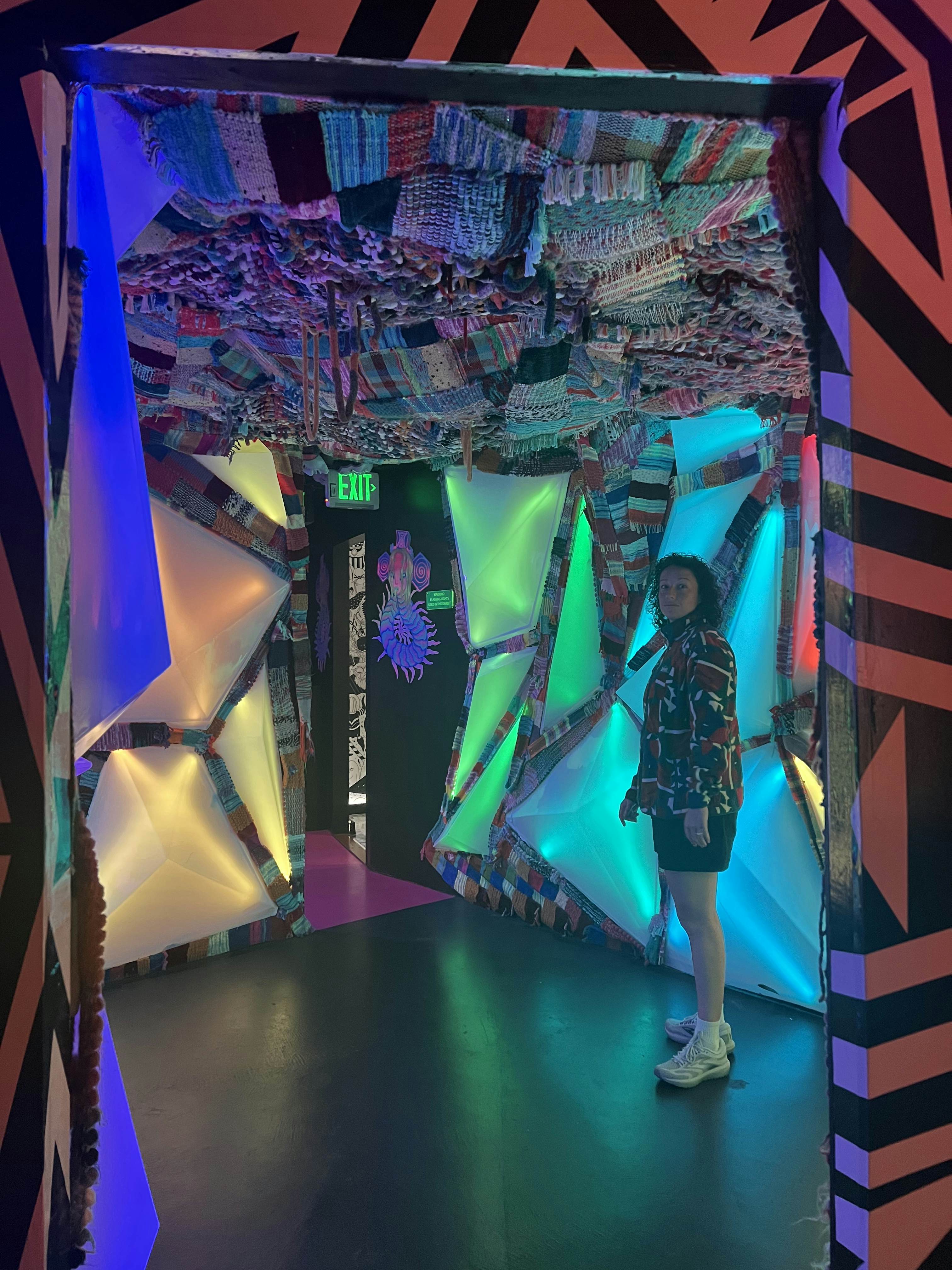 A person stands in a room with angled colored segments on the walls.