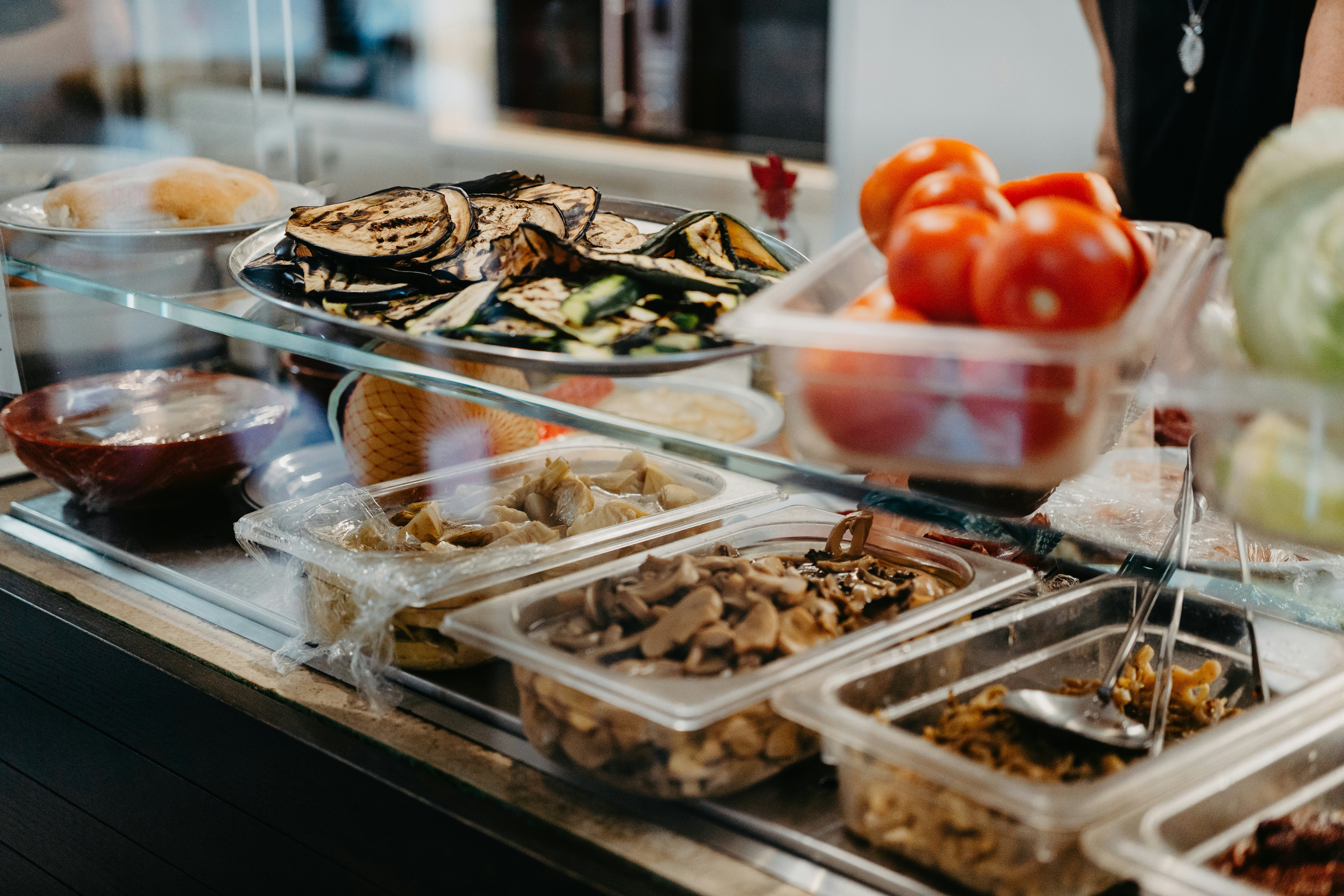 Fresh vegetables and other ingredients are displayed on the counter of a take-out restaurant.