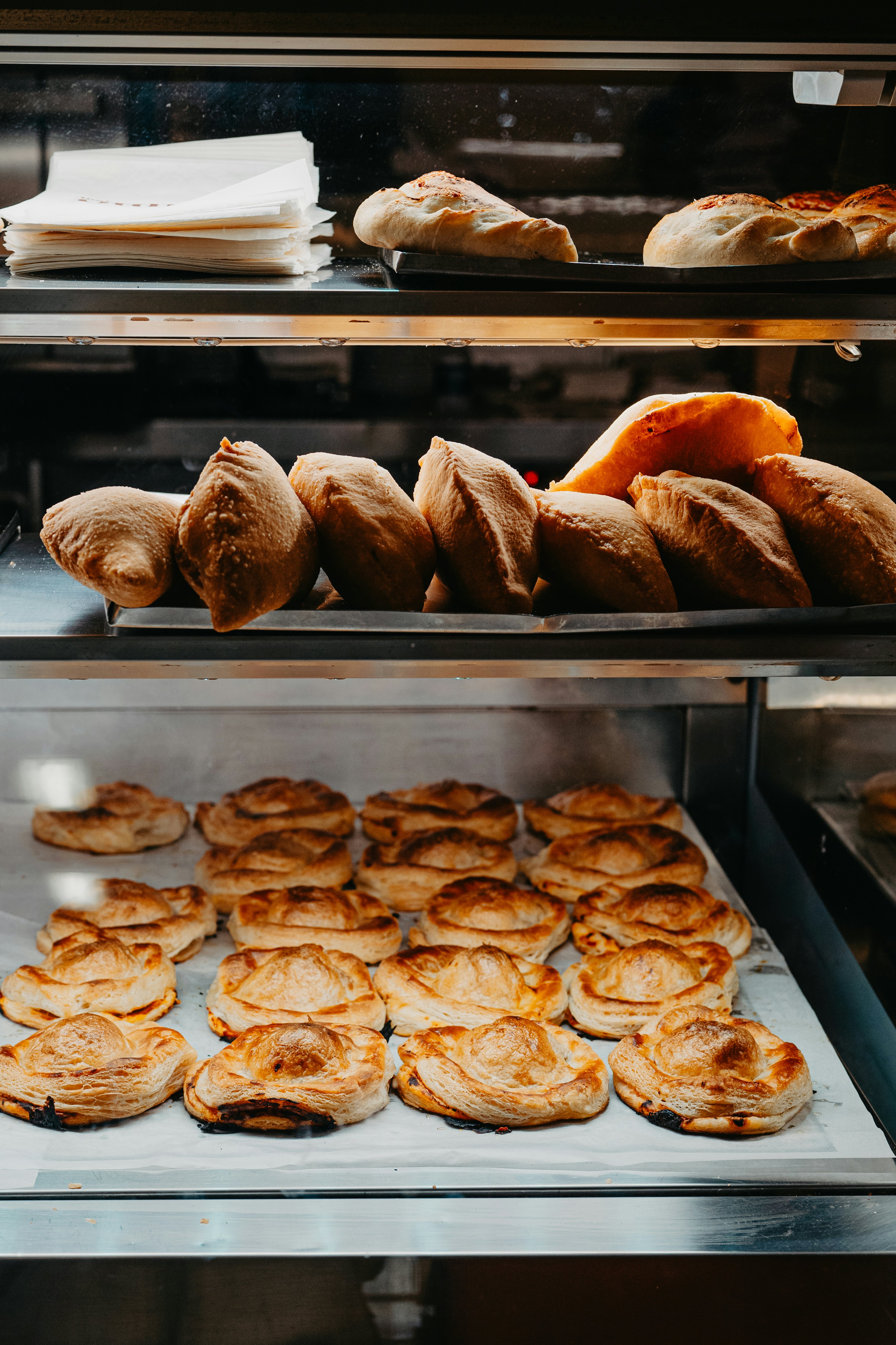 Typical food Calzone on the 1st and 2nd shelf (fried pizza dough filled with mozzarella and tomato. Many call it panzerotto but in Salento it is called Calzone). Rustico on the bottom (Baked puff pastry filled with bechamel, tomato, mozzarella)- Caffè Alvino