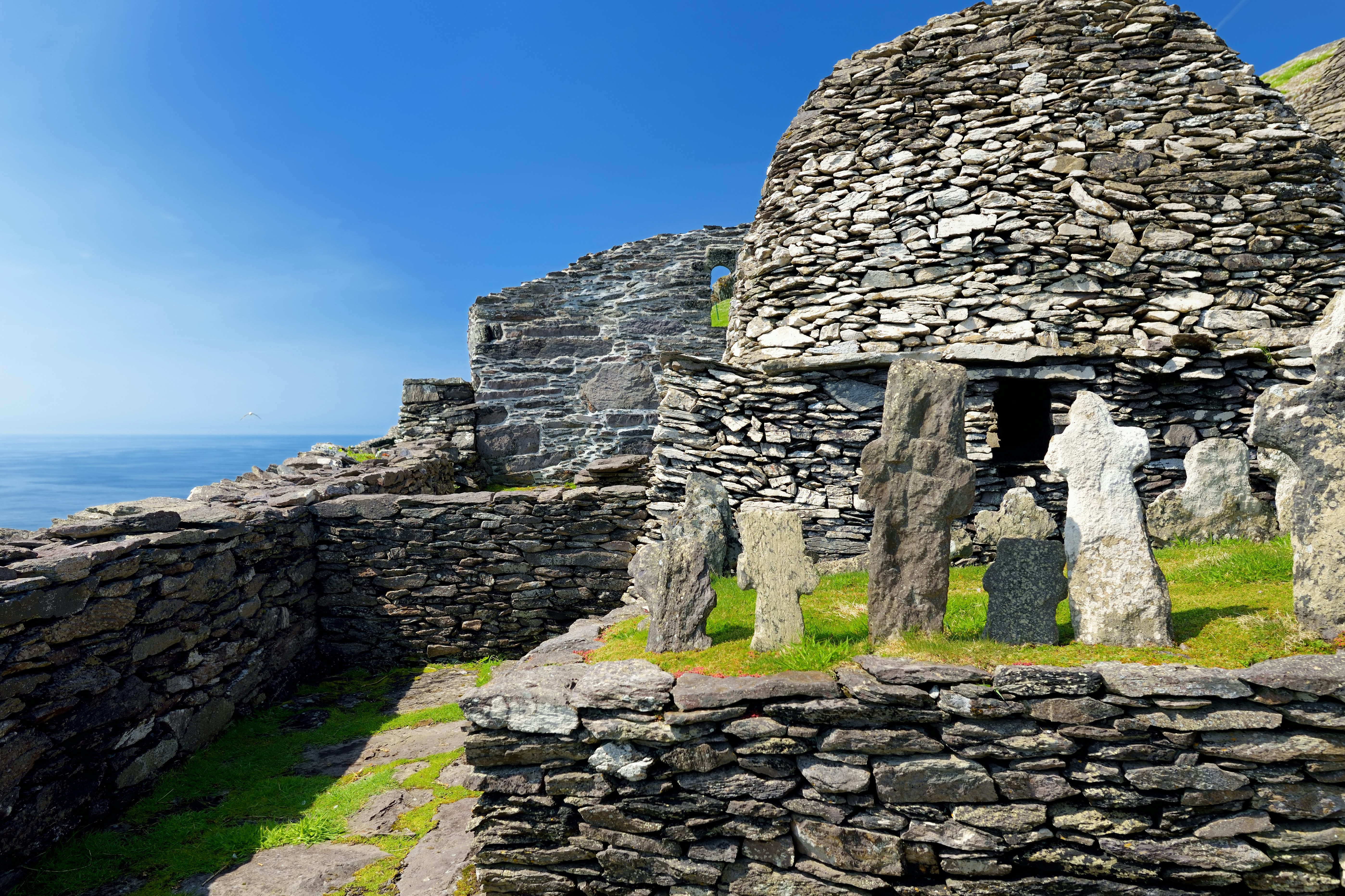 The rocky ruins of a building with stone markers that look like tombstones in the foreground