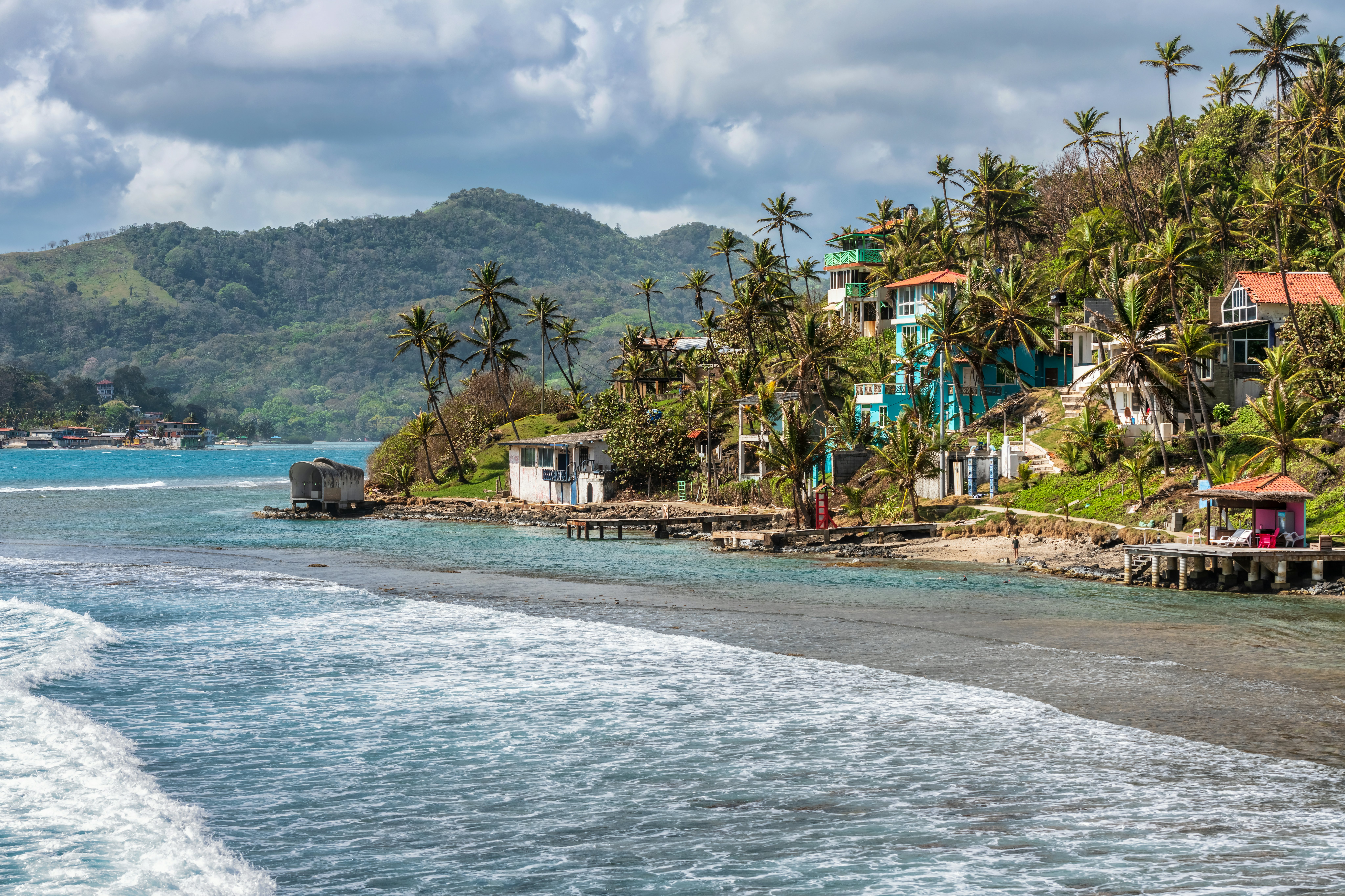 View at Palm trees, sea and houses in Isla Grande shore. Colon province, Panama, Caribbean, Central America.