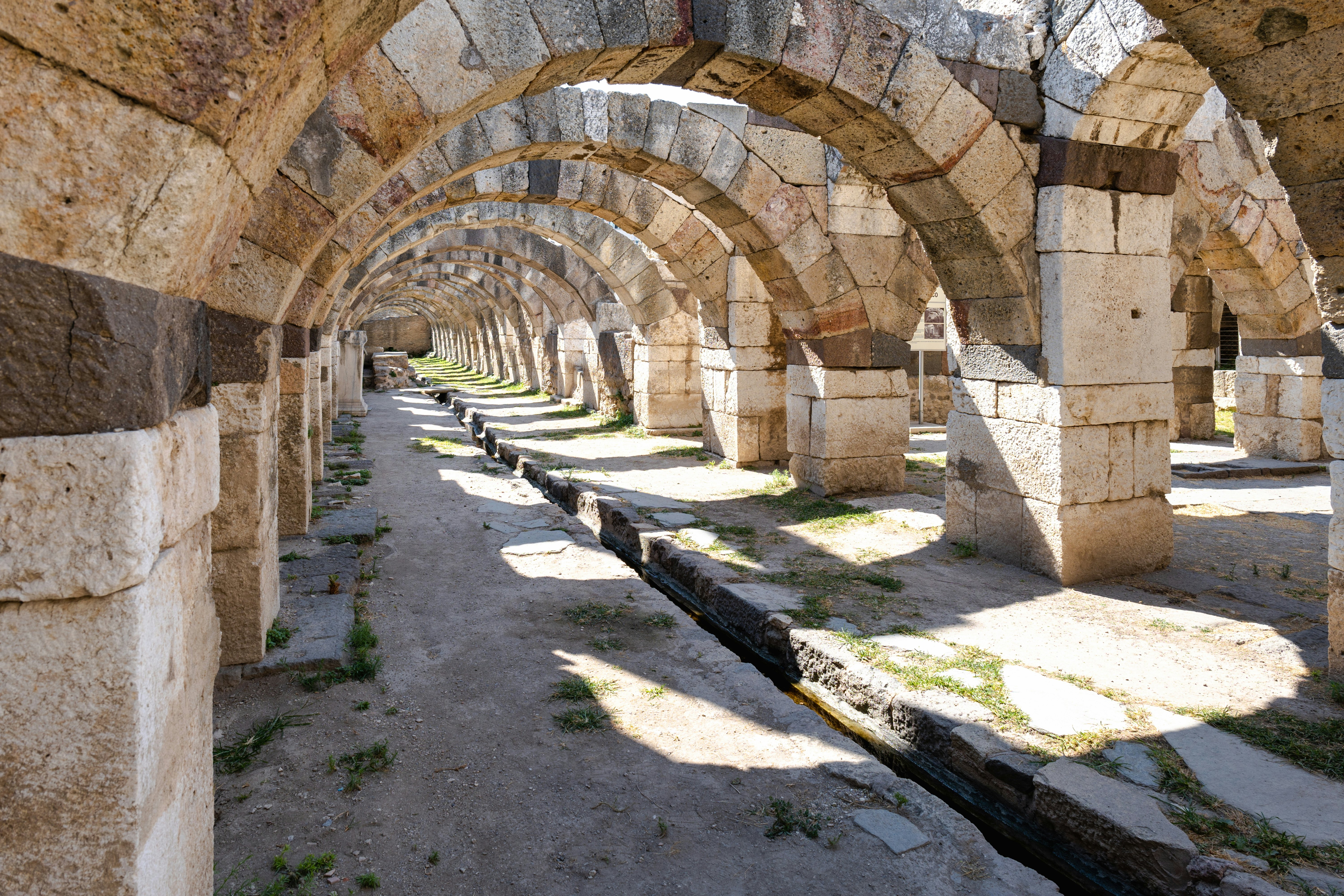 Sunlight pierces of a series of dozens of arches at an ancient archaeological site.