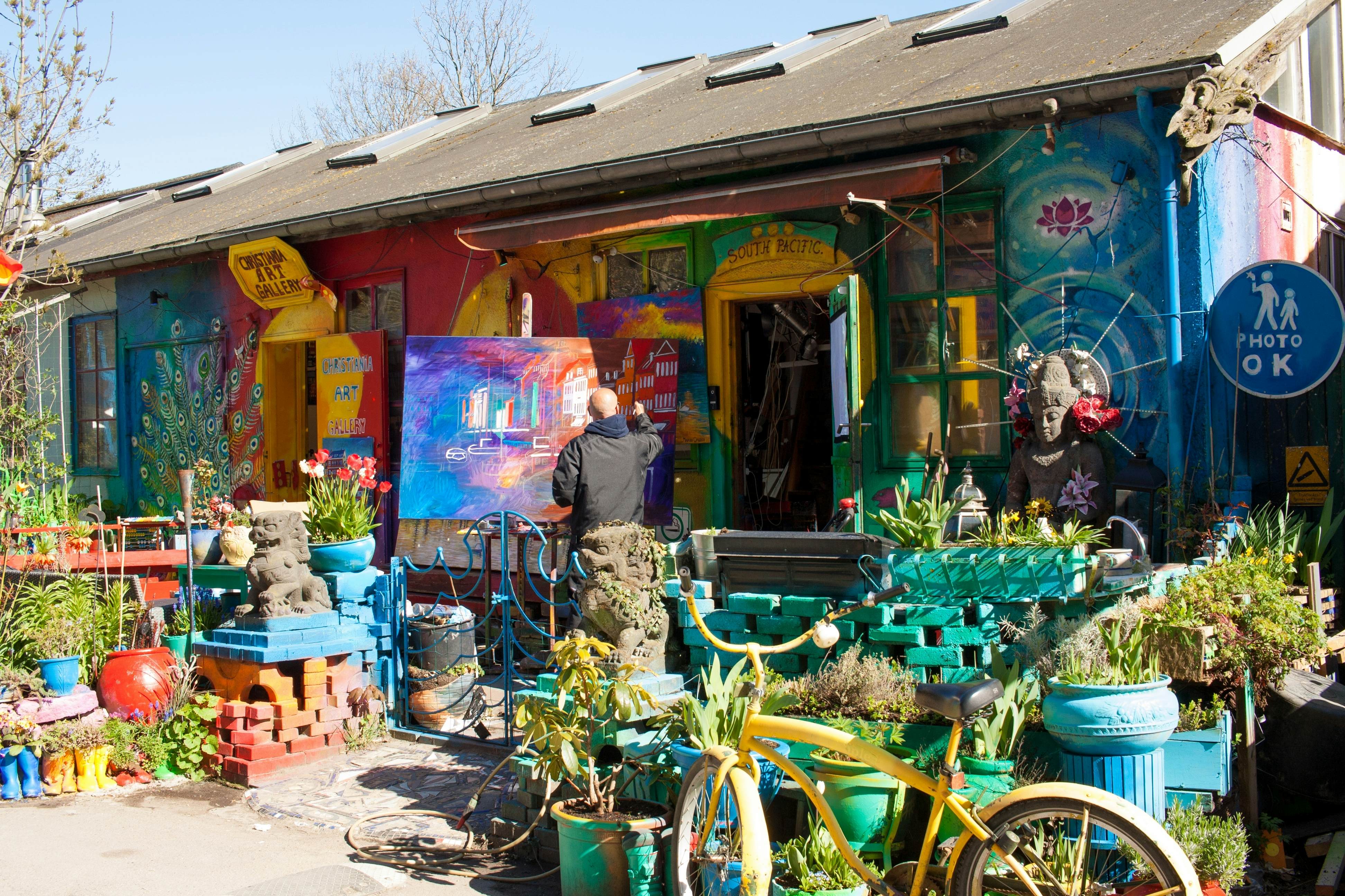 A painter outside a colorfully painted art gallery.