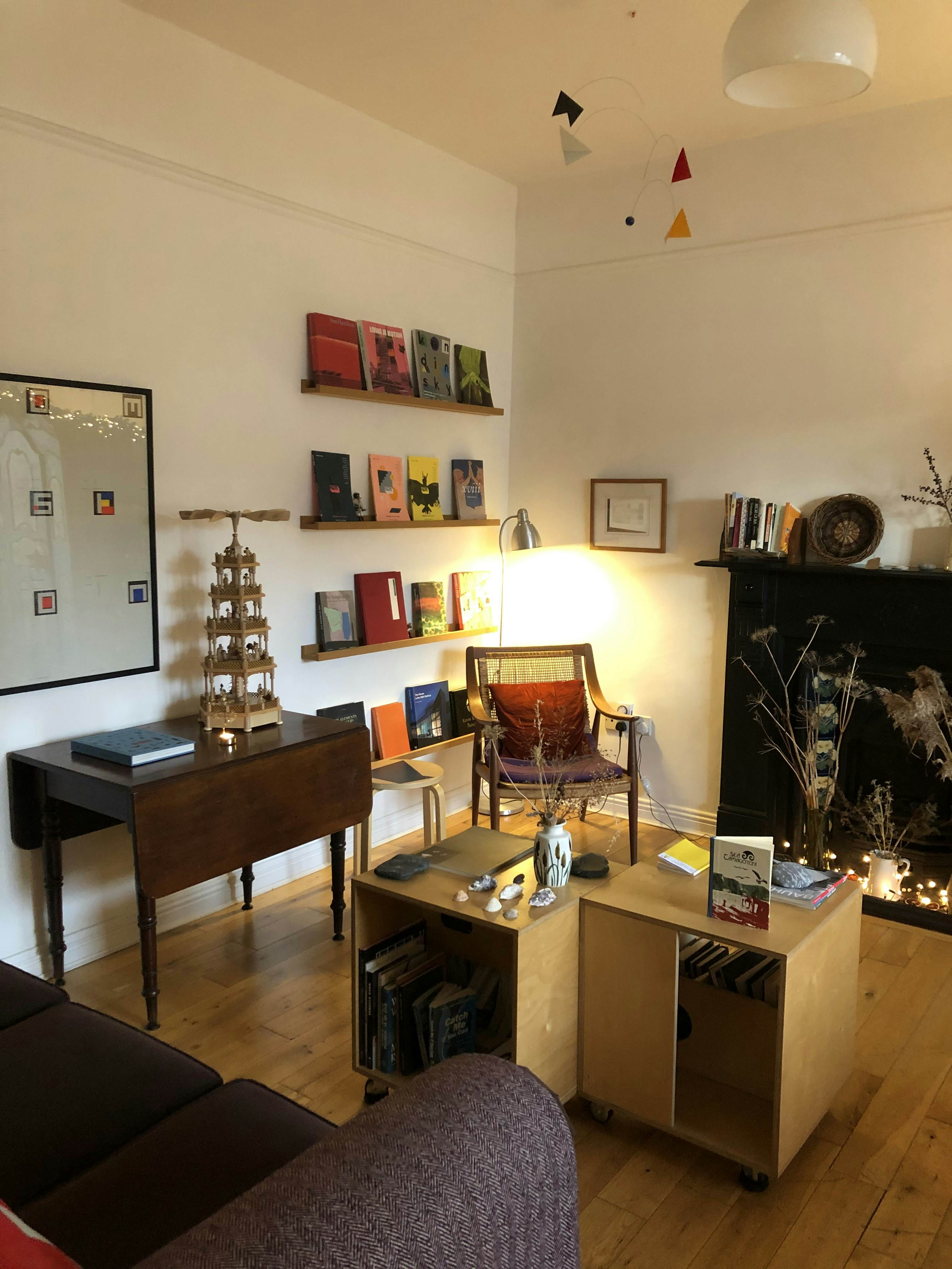 A chair in a corner by narrow shelves on the wall; a dark wooden table with leaves down is by the wall.