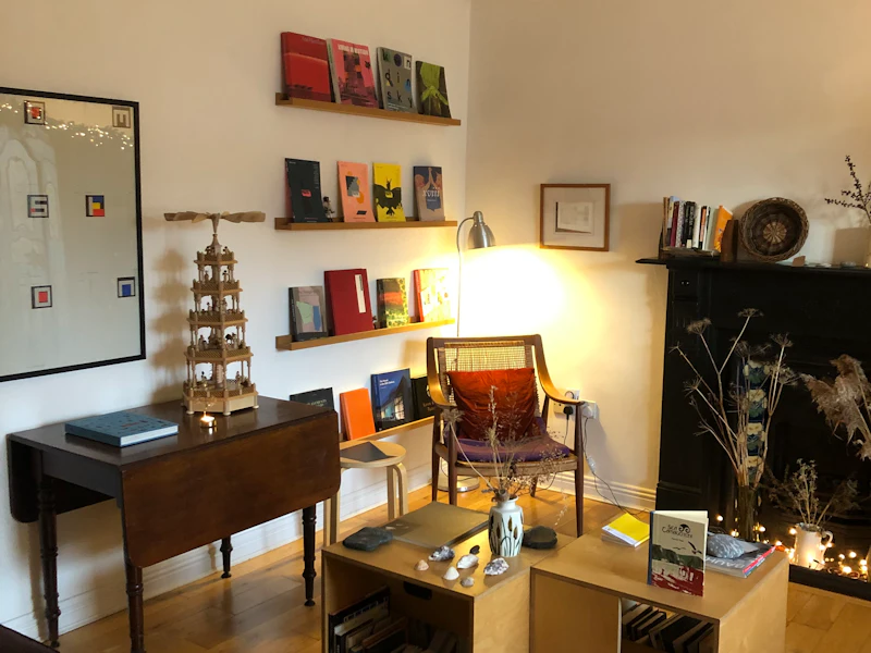A chair in a corner by narrow shelves on the wall; a dark wooden table with leaves down is by the wall.