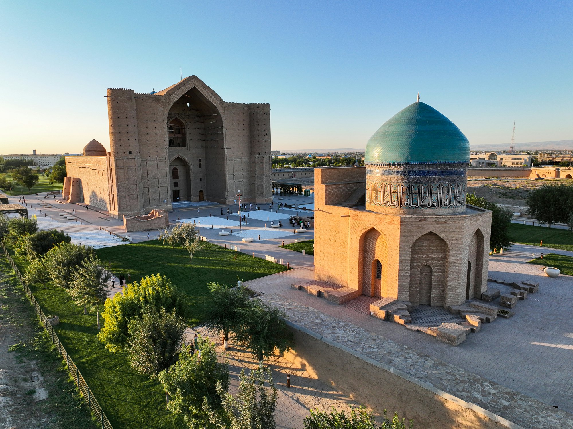 Large brick mausoleum buildings, one with a large blue dome, in a square.