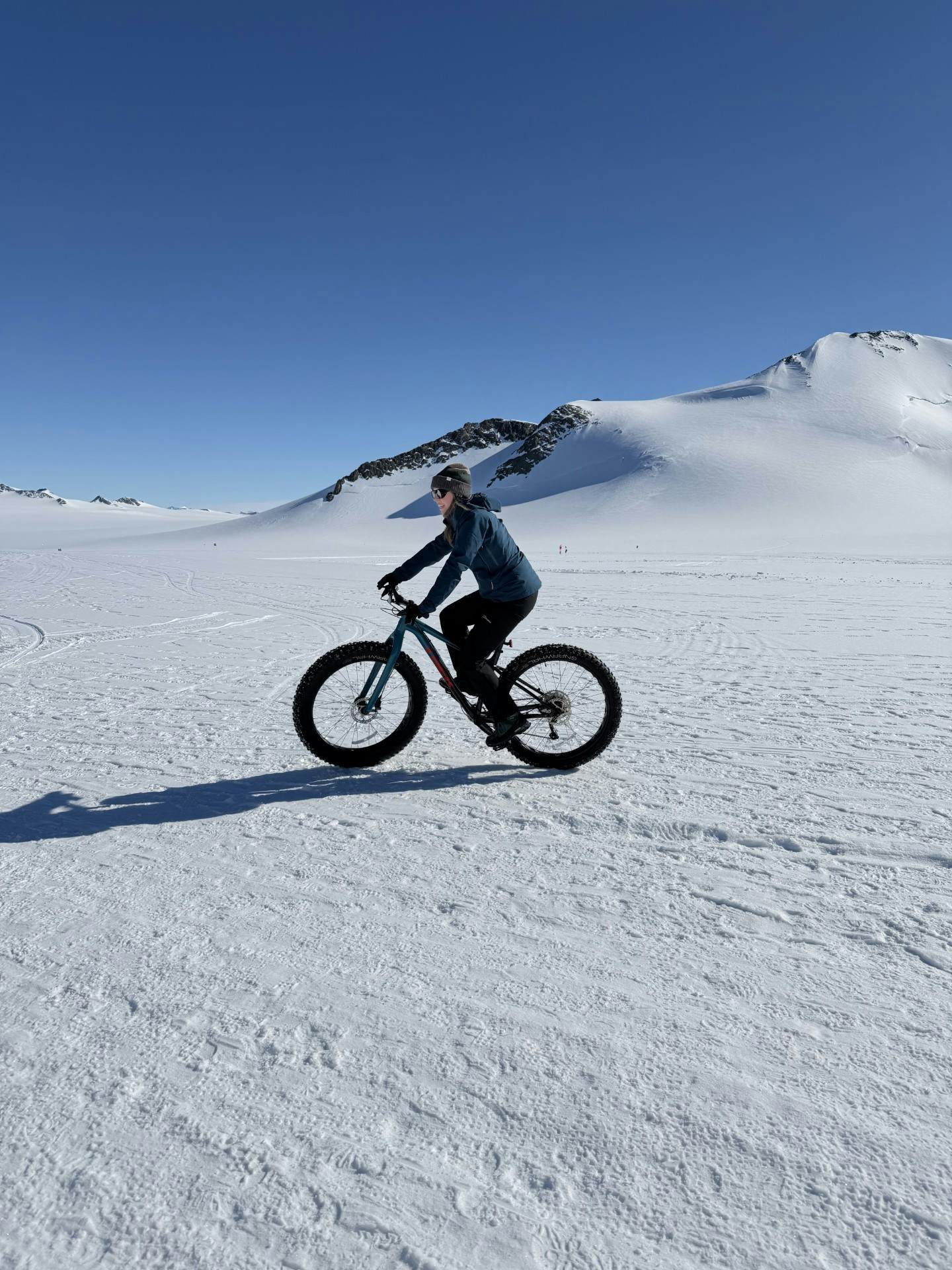 A woman rides a bike with thick tires through snow.