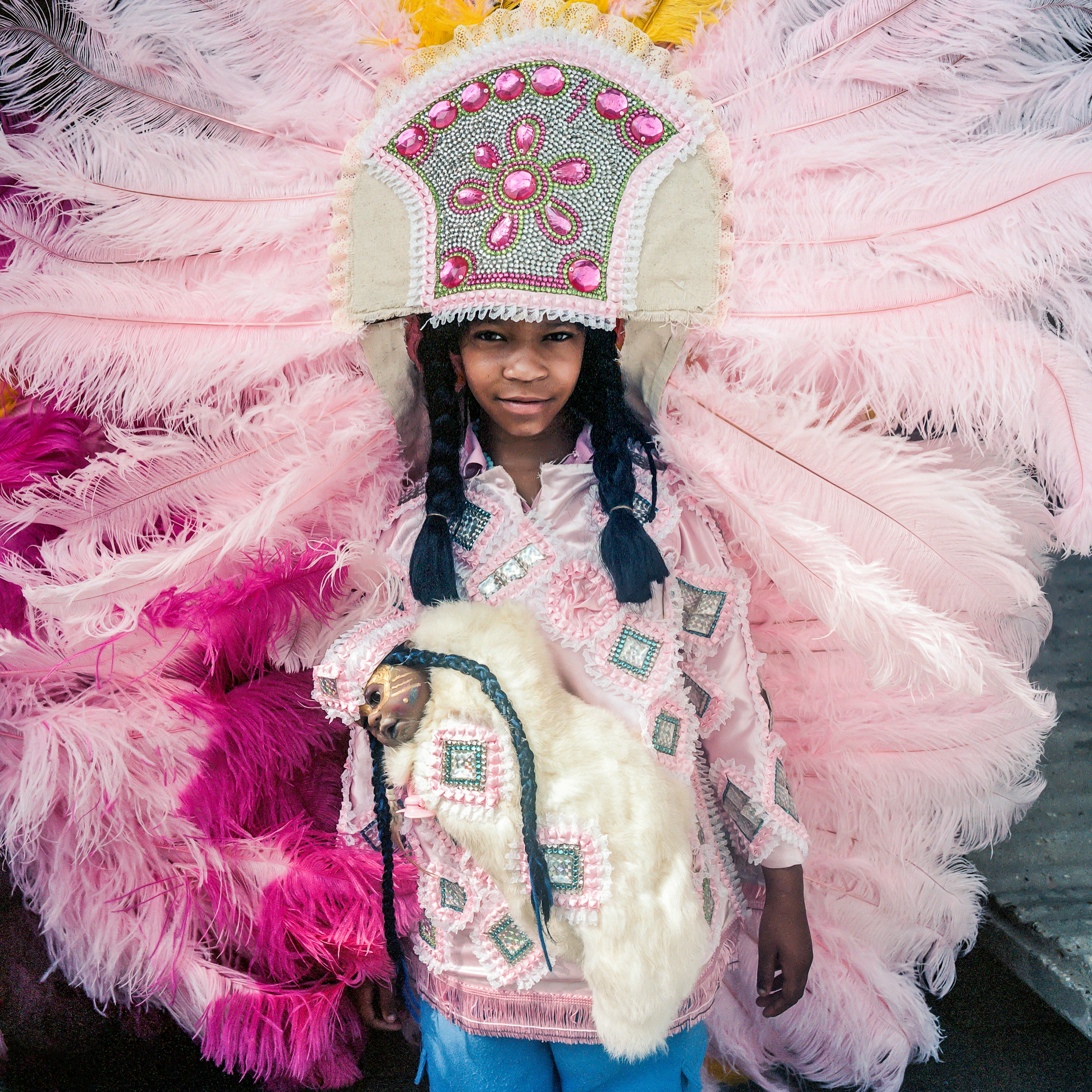A person wears a costume with a massive pink feathered headdress.