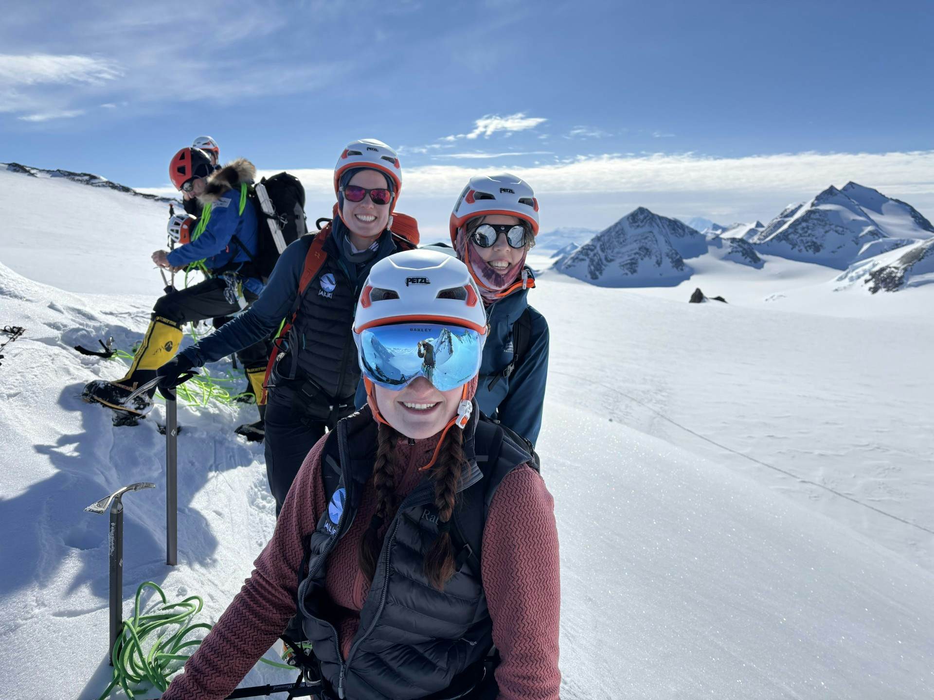 A group of people in cold-weather hiking gear pose together on a snow-covered mountain.