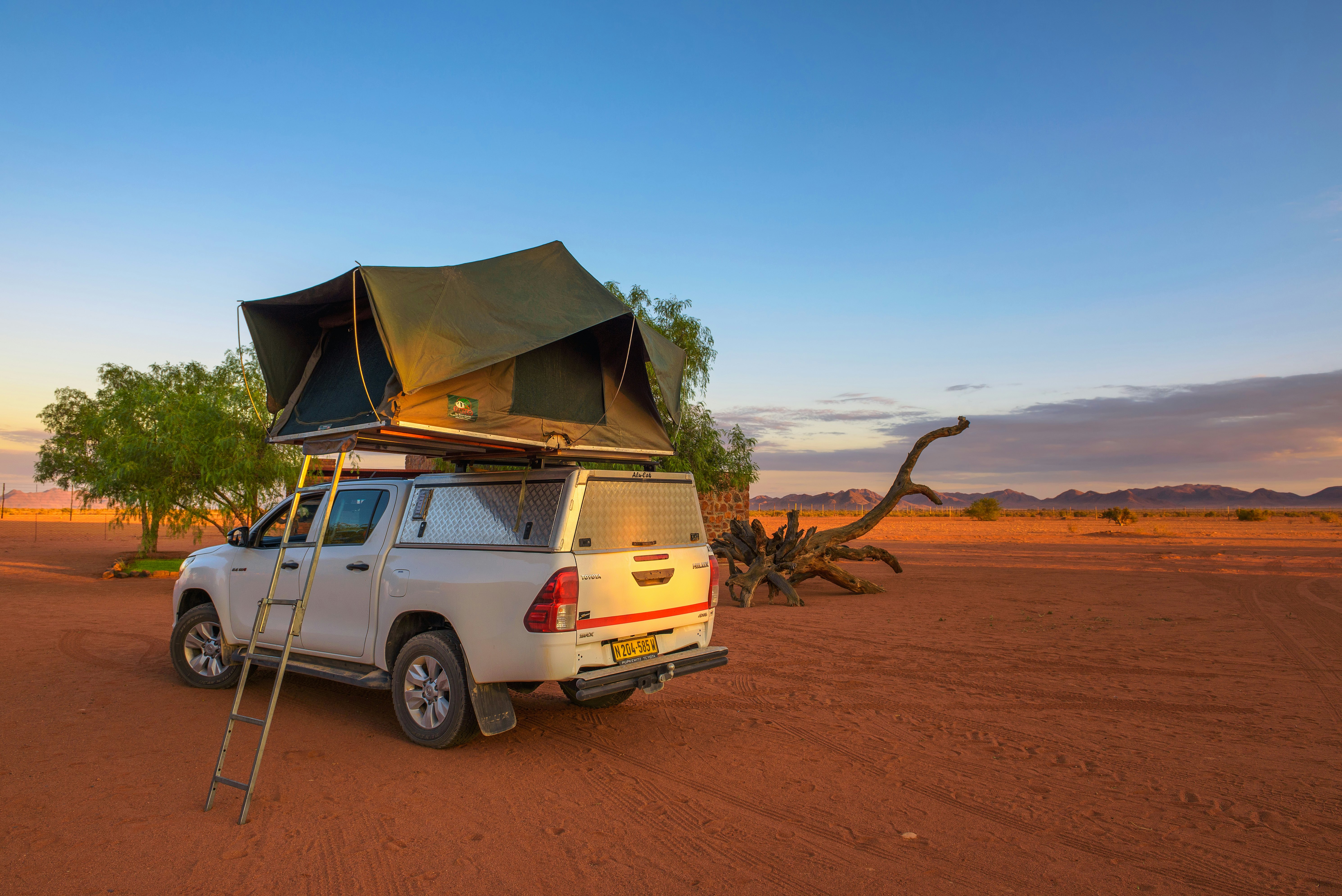 A tent is set up on the roof of a 4x4 parked in a remote desert.