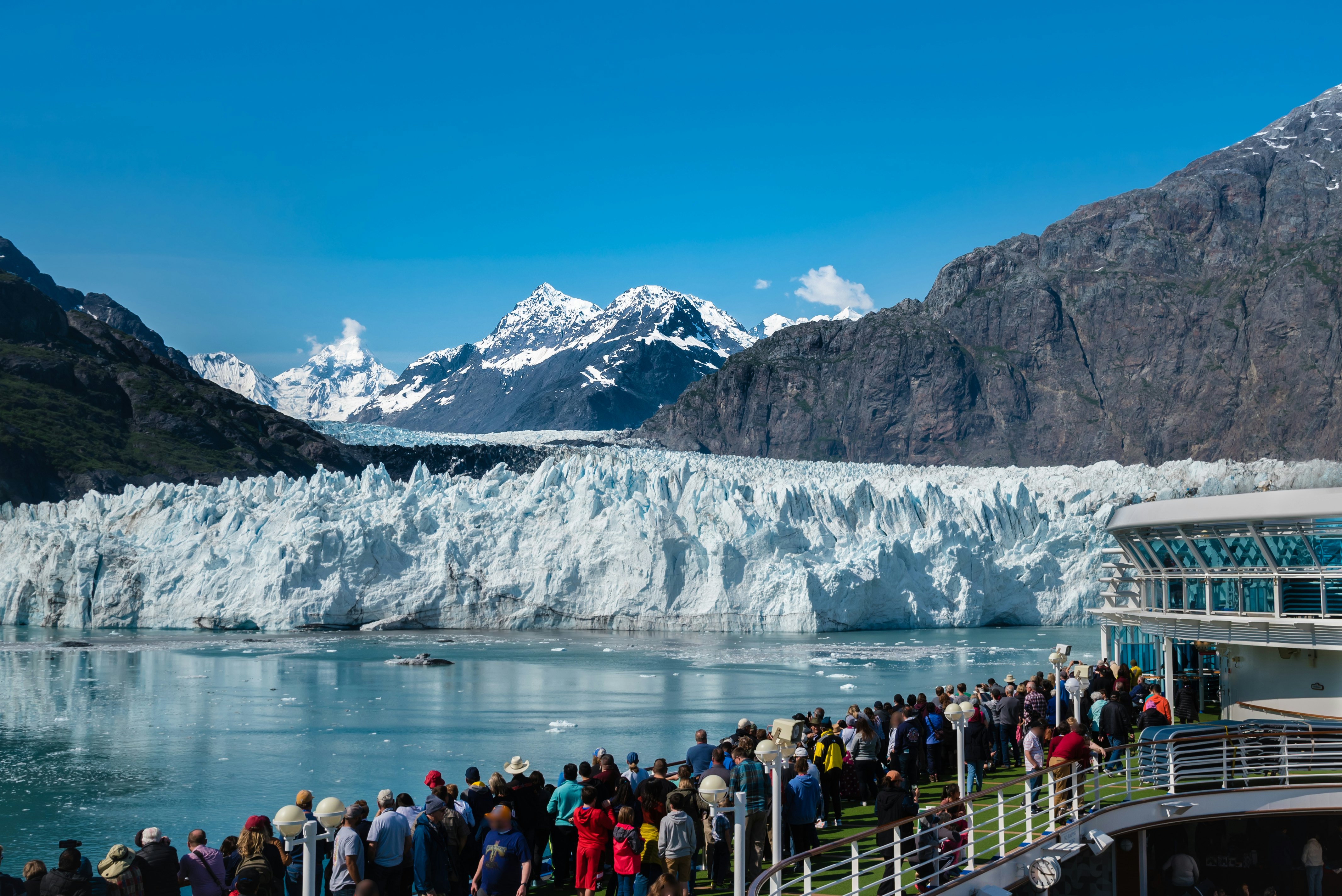 A group of tourists are enjoying the gorgeous view of the Margerie Glacier in the Glacier Bay of Alaska on a sunny day.