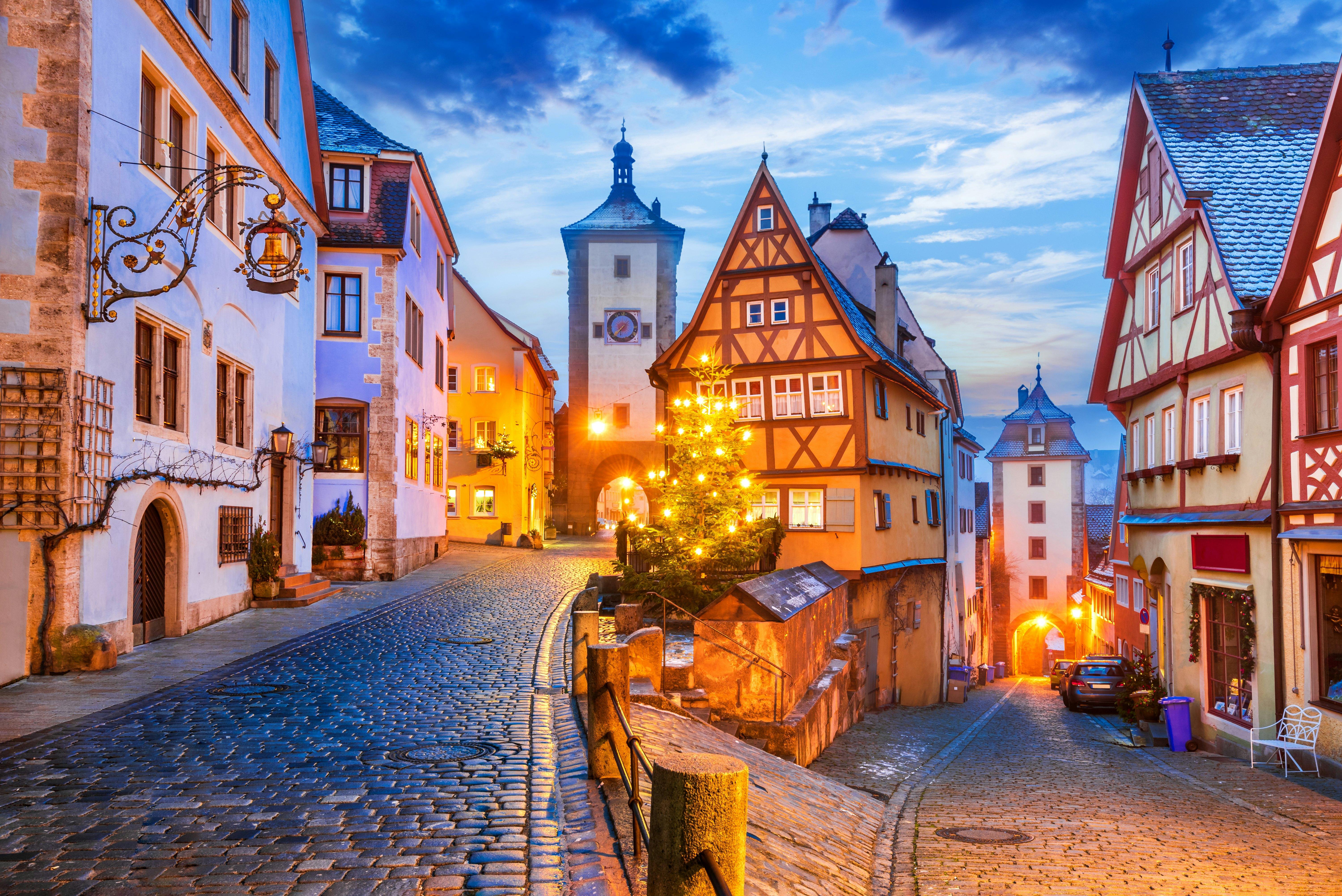 A view of a medieval town with half-timbered buildings and cobbled streets at dusk.