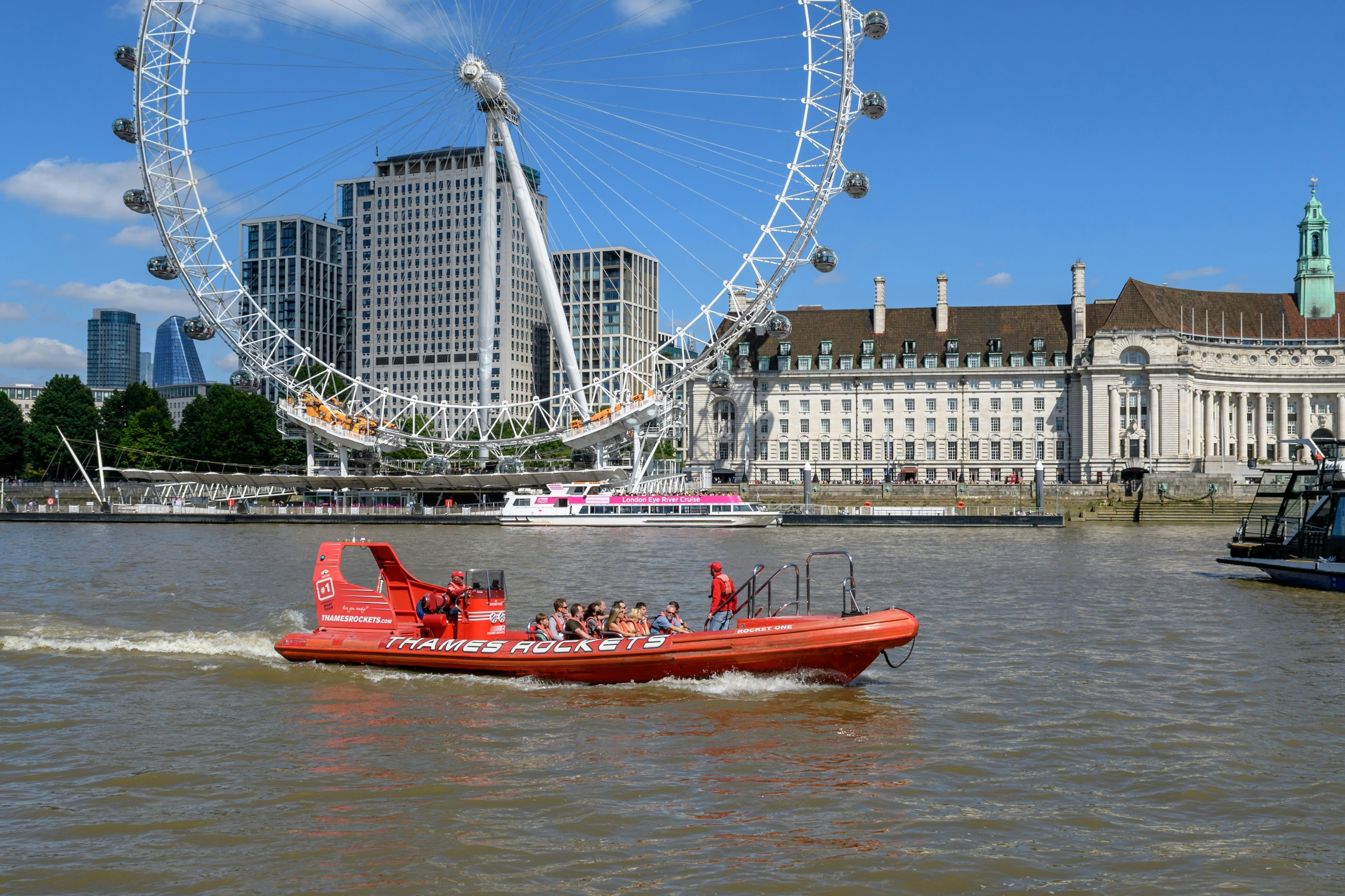 London - July 7, 2022: An Thames Rocket boat carries passengers on the River Thames in front of the London Eye.